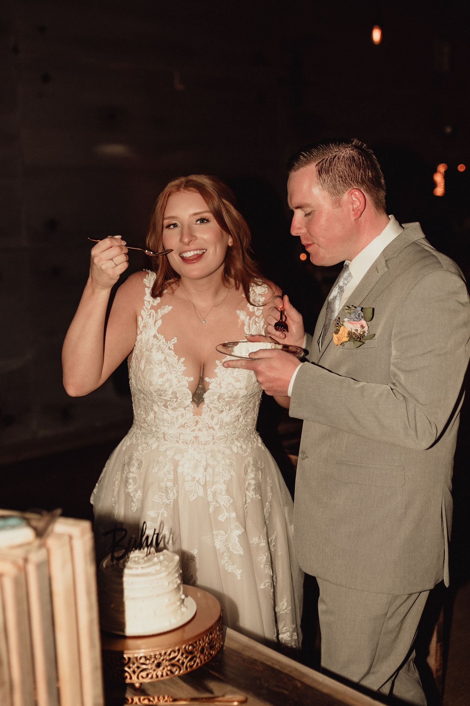 A couple shares a piece of wedding cake together during their reception celebration.