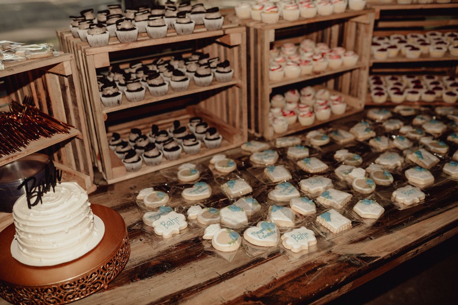 Rows of delicate white and blue cupcakes displayed on wooden shelves in a bakery setting.