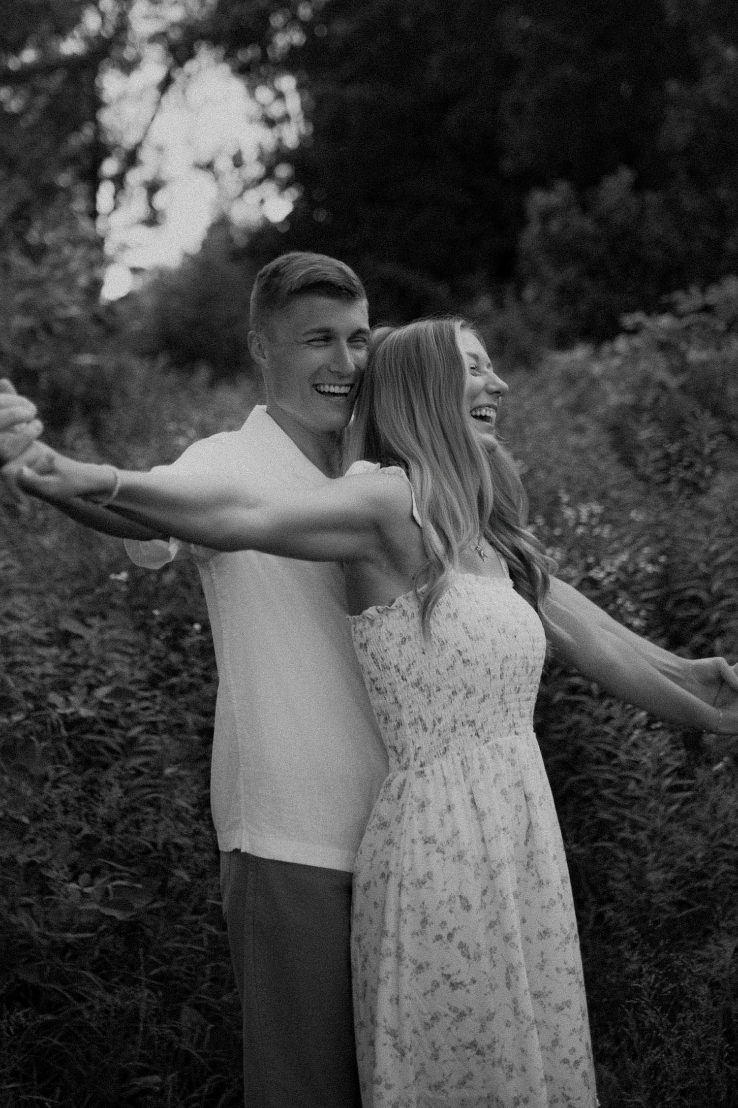 A joyful couple embraces while enjoying a candid moment in a garden setting.