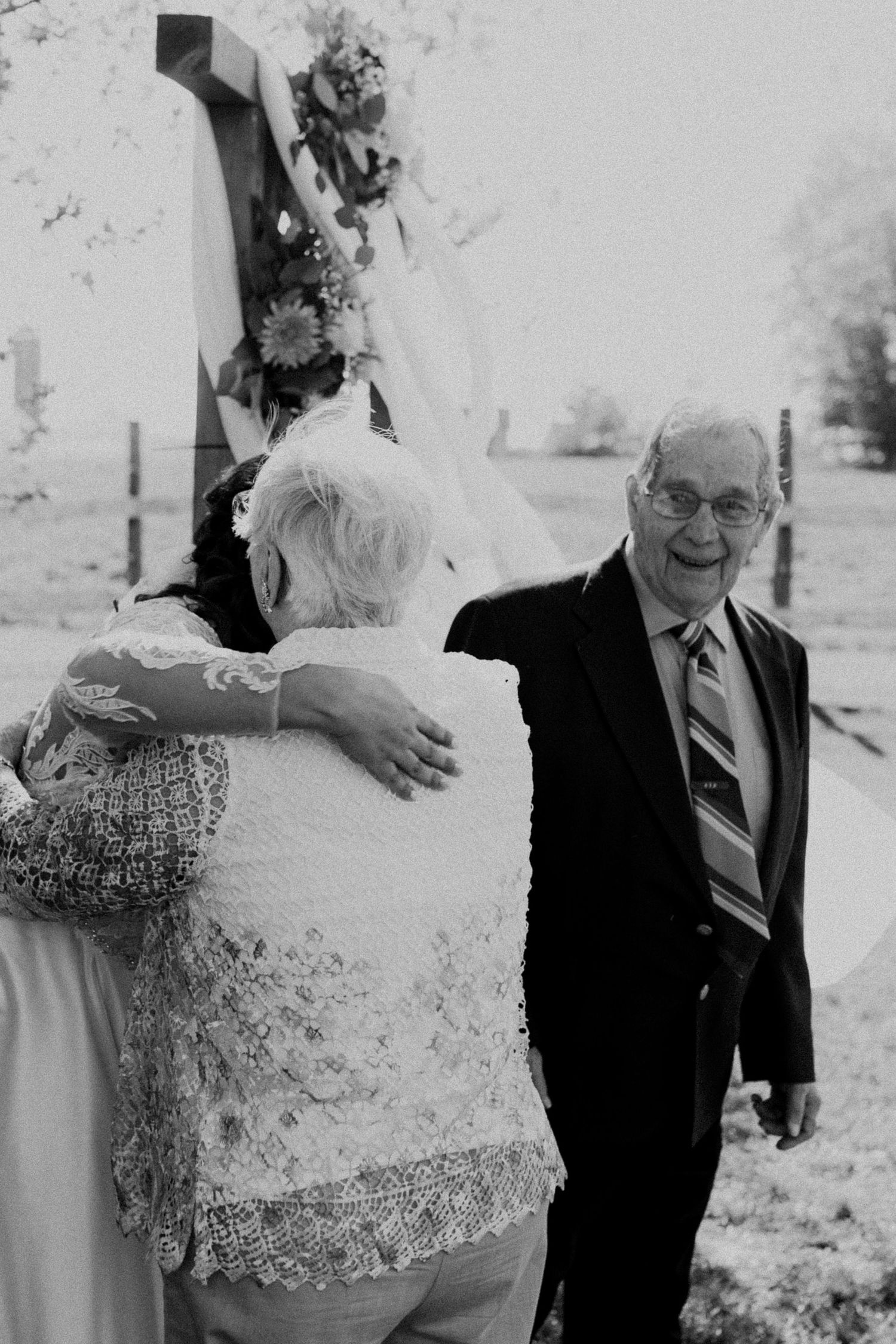 A vintage black and white photo showing a heartwarming embrace at an outdoor gathering.
