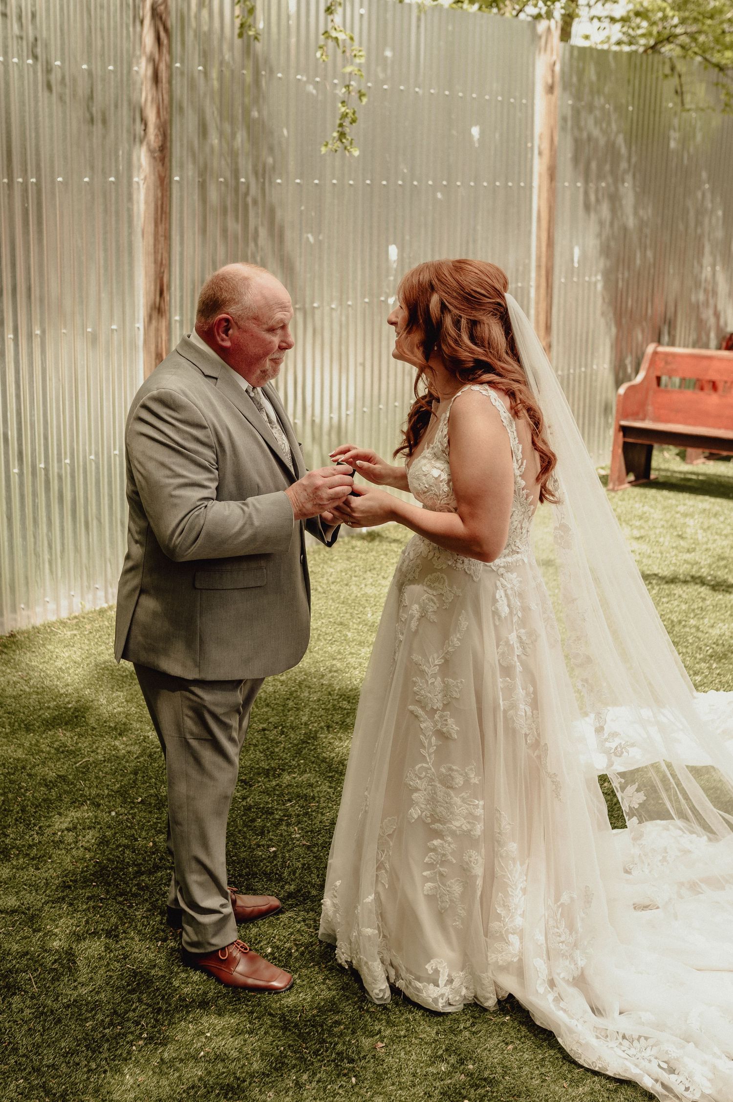 A tender moment captured at an outdoor wedding as two people share an emotional exchange on a grassy lawn.