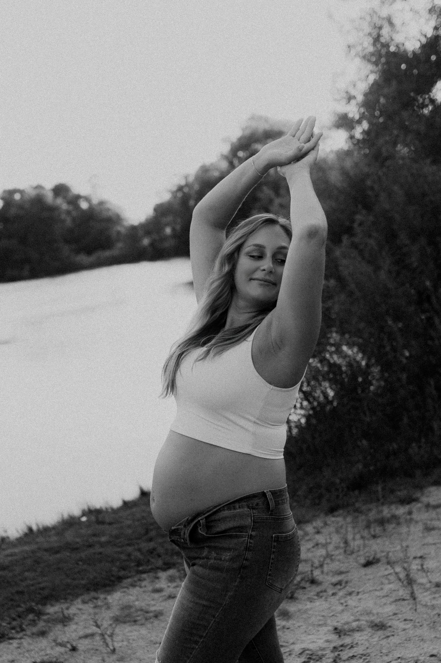 Black and white maternity portraits on sandy beach at sunset.