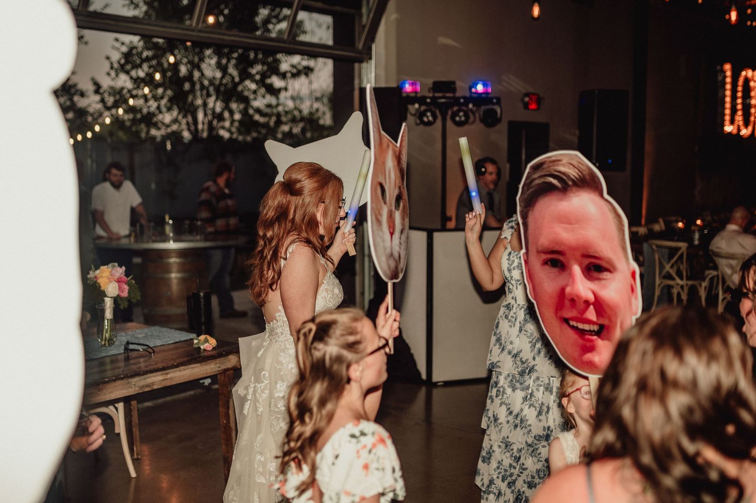 Wedding reception guests dancing and celebrating on a dimly lit dance floor with red lighting accents.