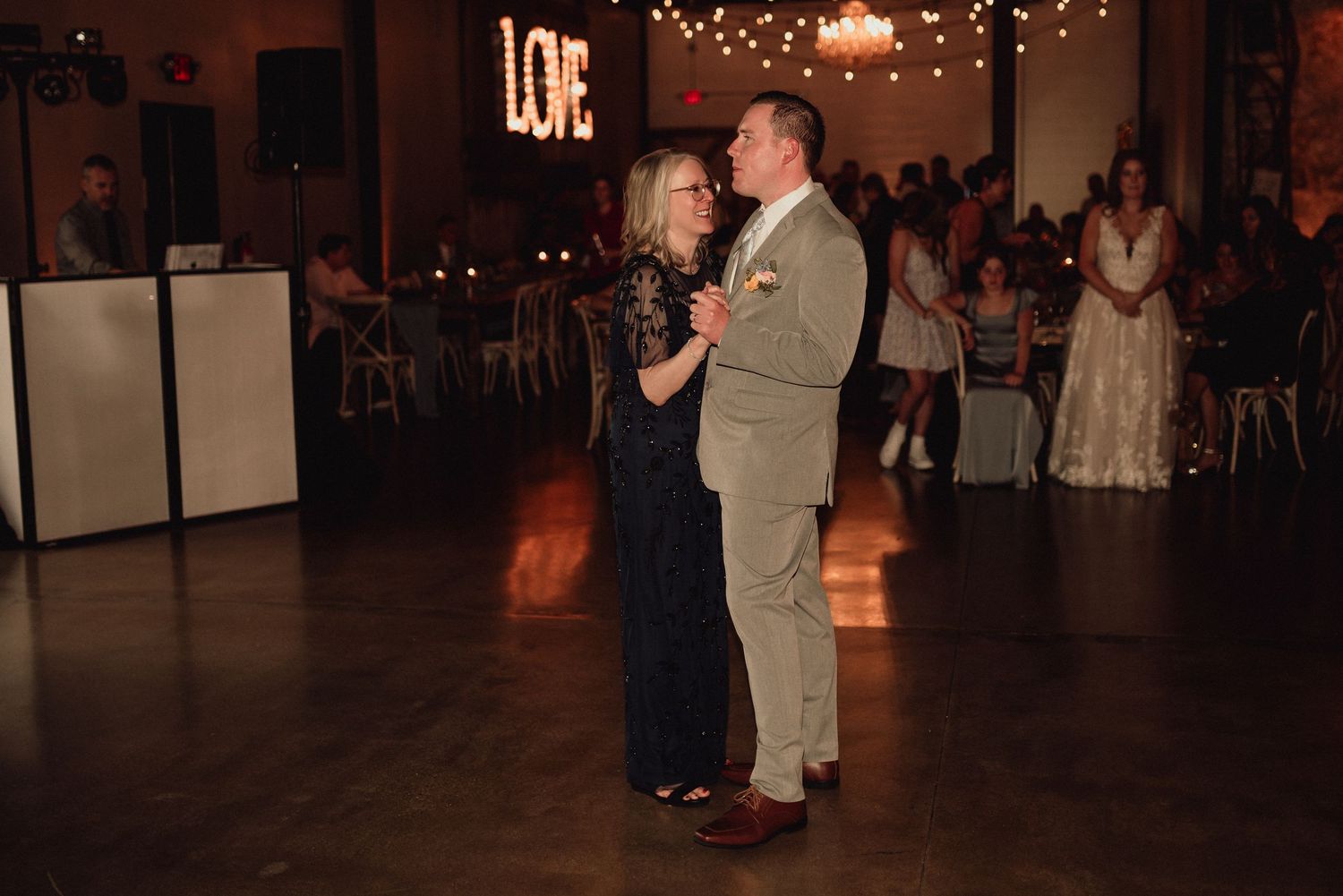 People dancing and socializing at an indoor event with warm lighting and decorative elements.