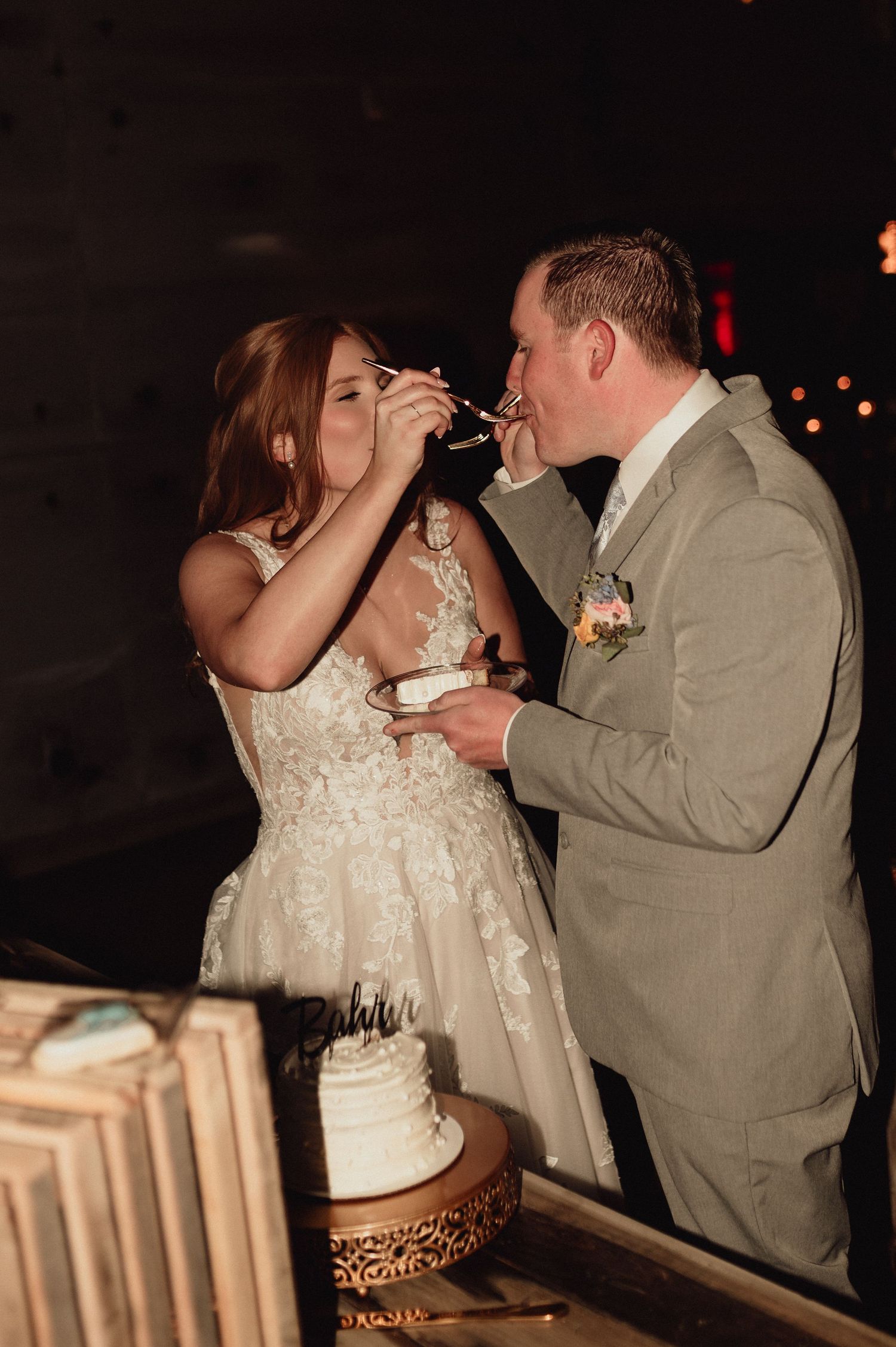 Bride and groom share their first bite of wedding cake together during their romantic reception celebration.
