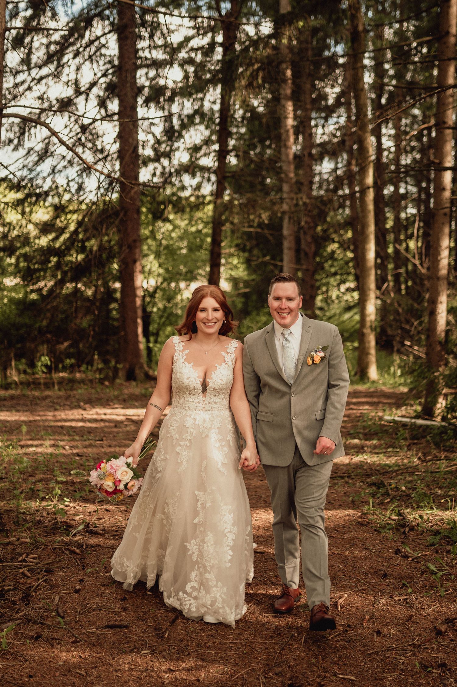 A couple shares a romantic moment in a forest setting, with sunlight filtering through tall pine trees.