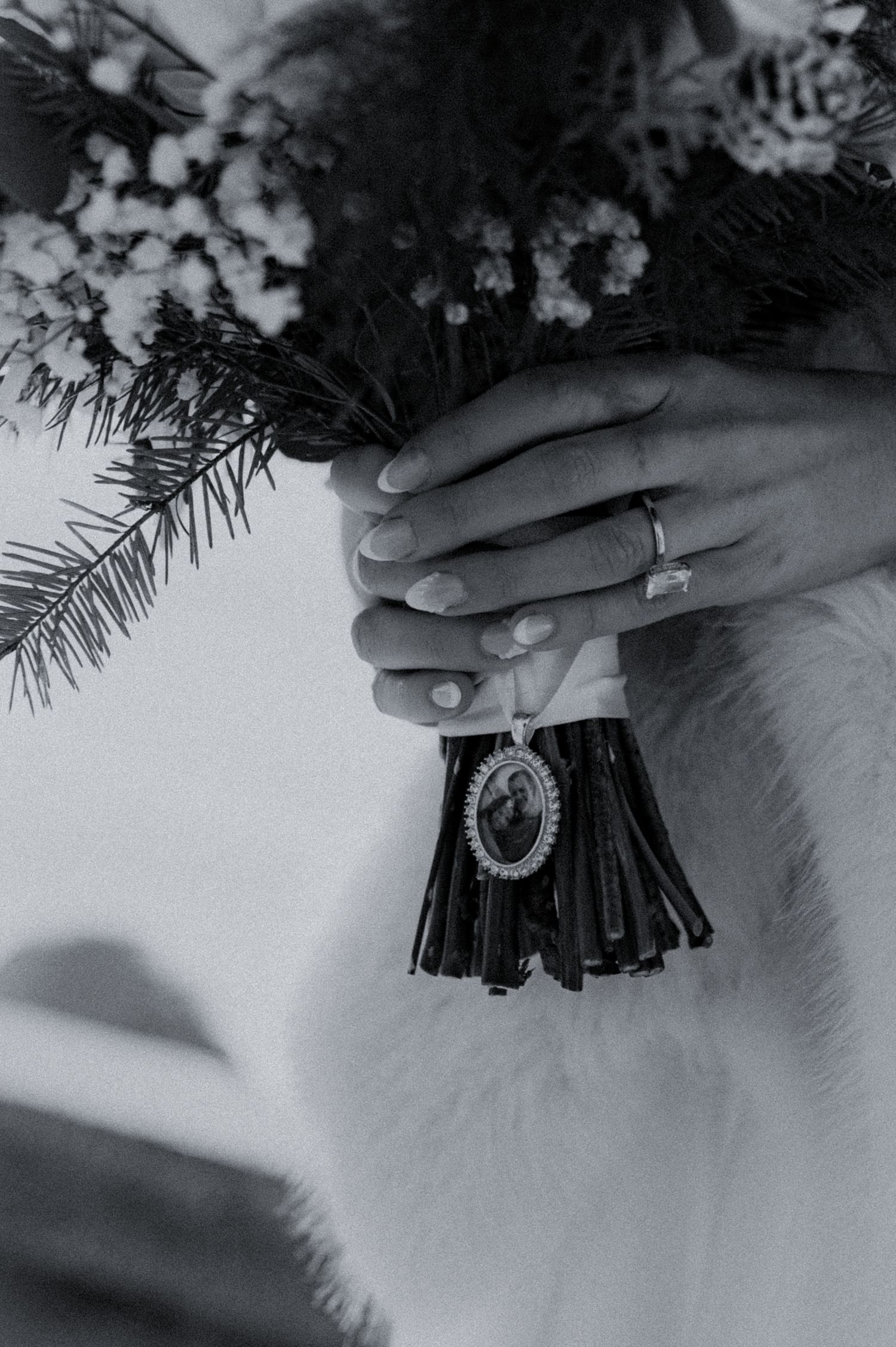 Black and white photo series showing hands holding a decorative pendant necklace against a textured background.