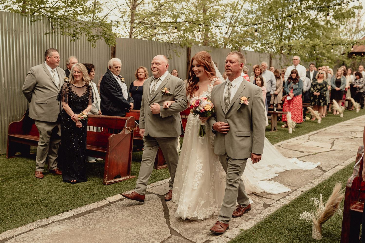 Wedding guests line up outside a rustic barn venue for a celebratory recessional moment.