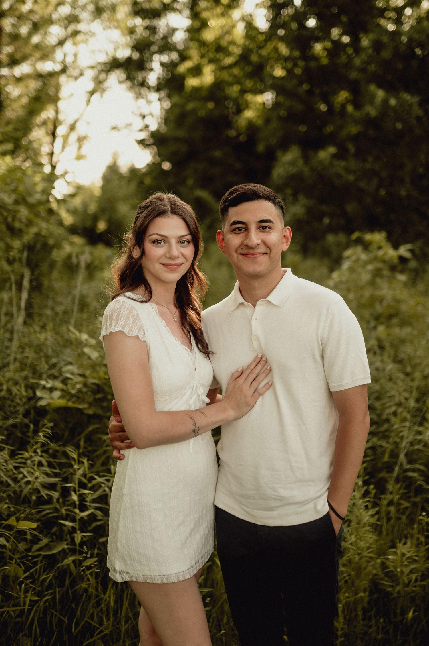 A romantic engagement photo in a natural outdoor setting with golden evening light.