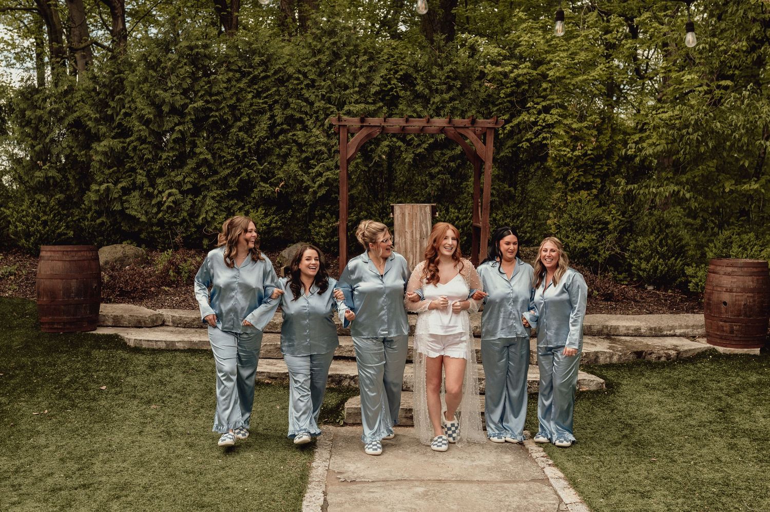 A group of people in coordinated denim outfits sit together on stone steps in a garden setting.