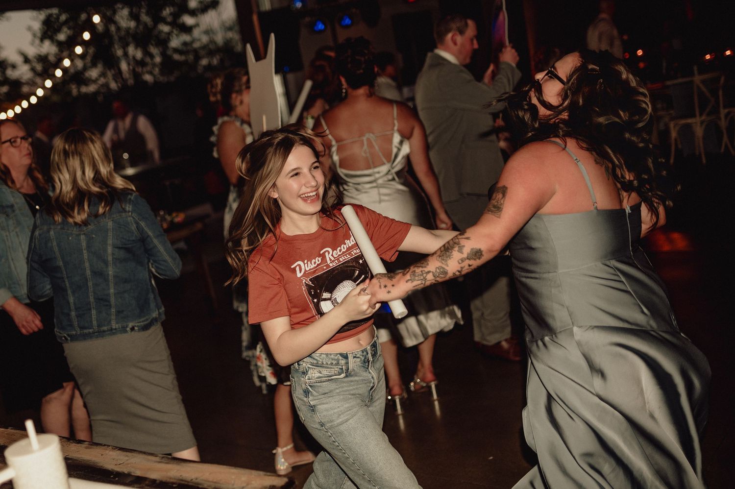 A group of people dancing and socializing at a dimly lit party venue with festive lighting.