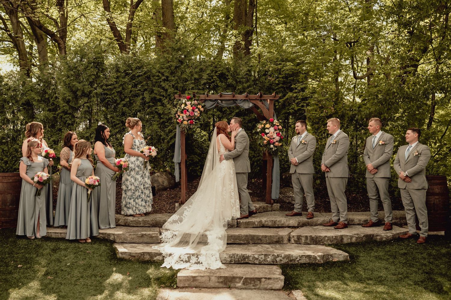 Wedding ceremony setup in lush garden setting with stone pathway and natural decor.