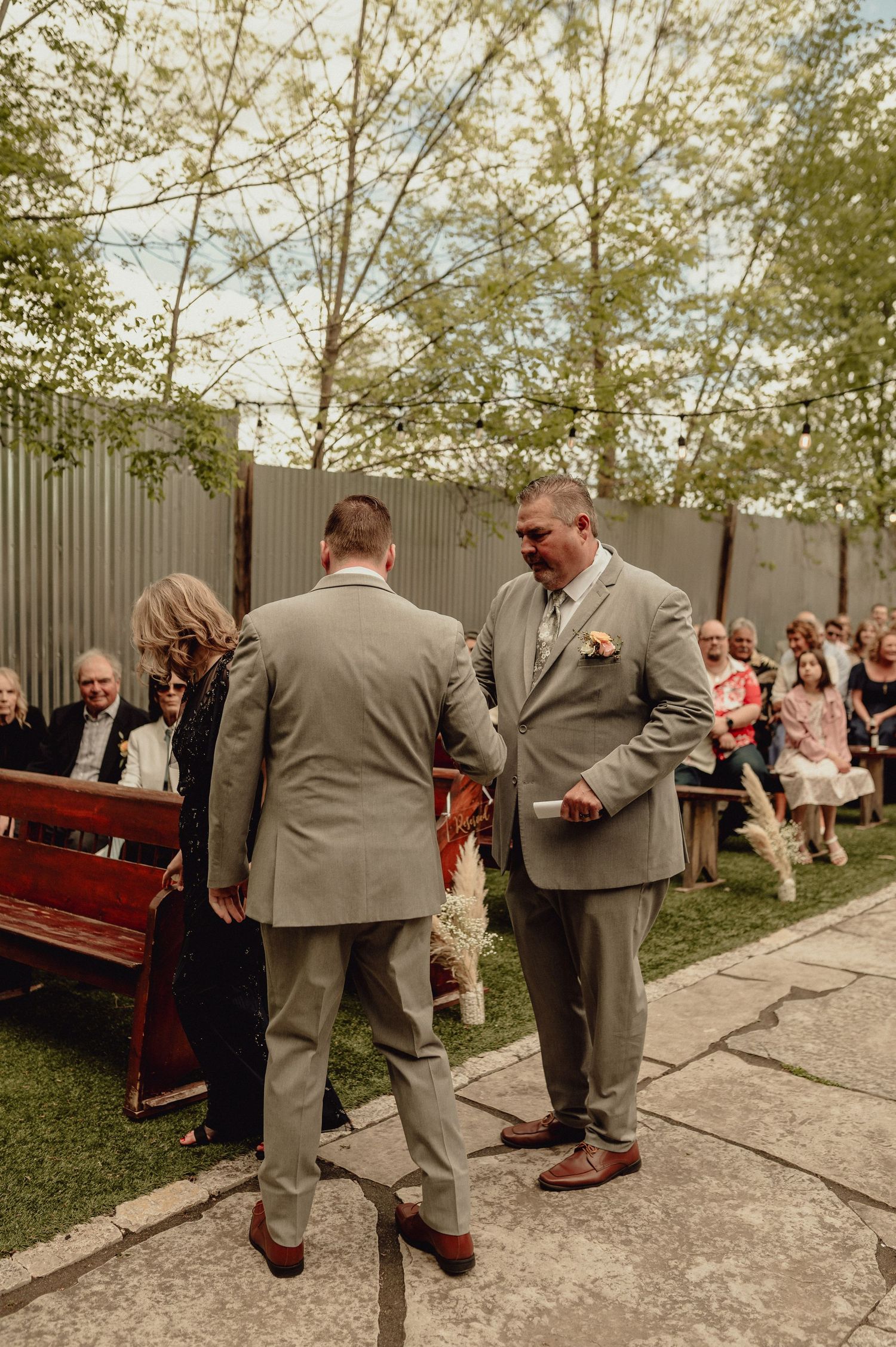 A sequence of playful groomsmen jumping in unison during an outdoor wedding ceremony.