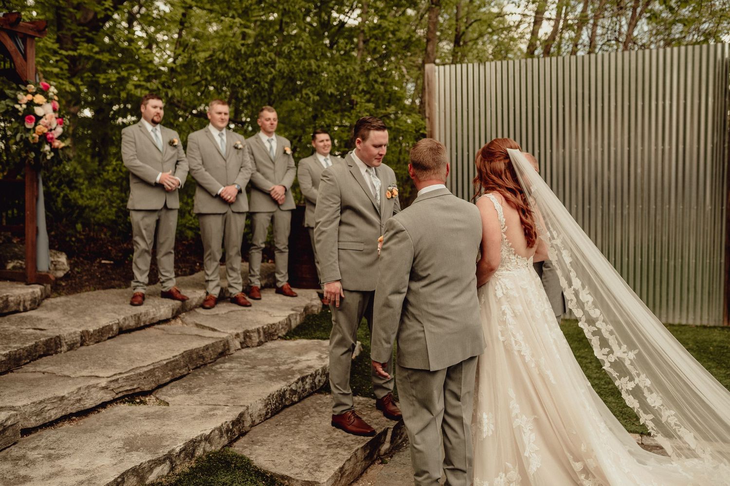 A wedding party in gray suits and a white dress pose together in a series of candid outdoor photos.