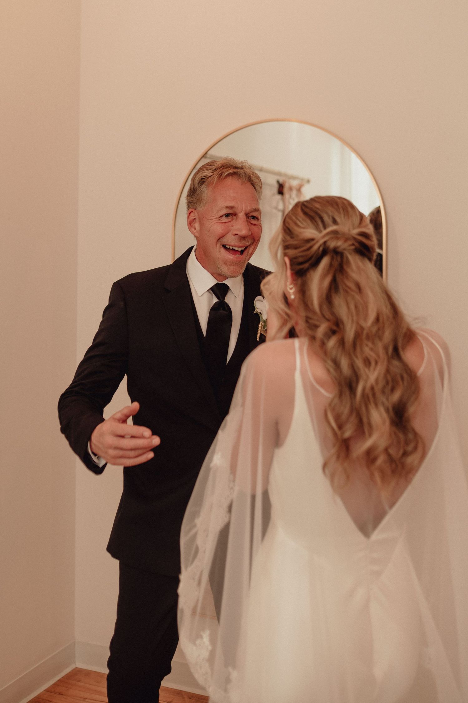 A touching first look moment between a bride and her father in a hallway before the wedding ceremony.