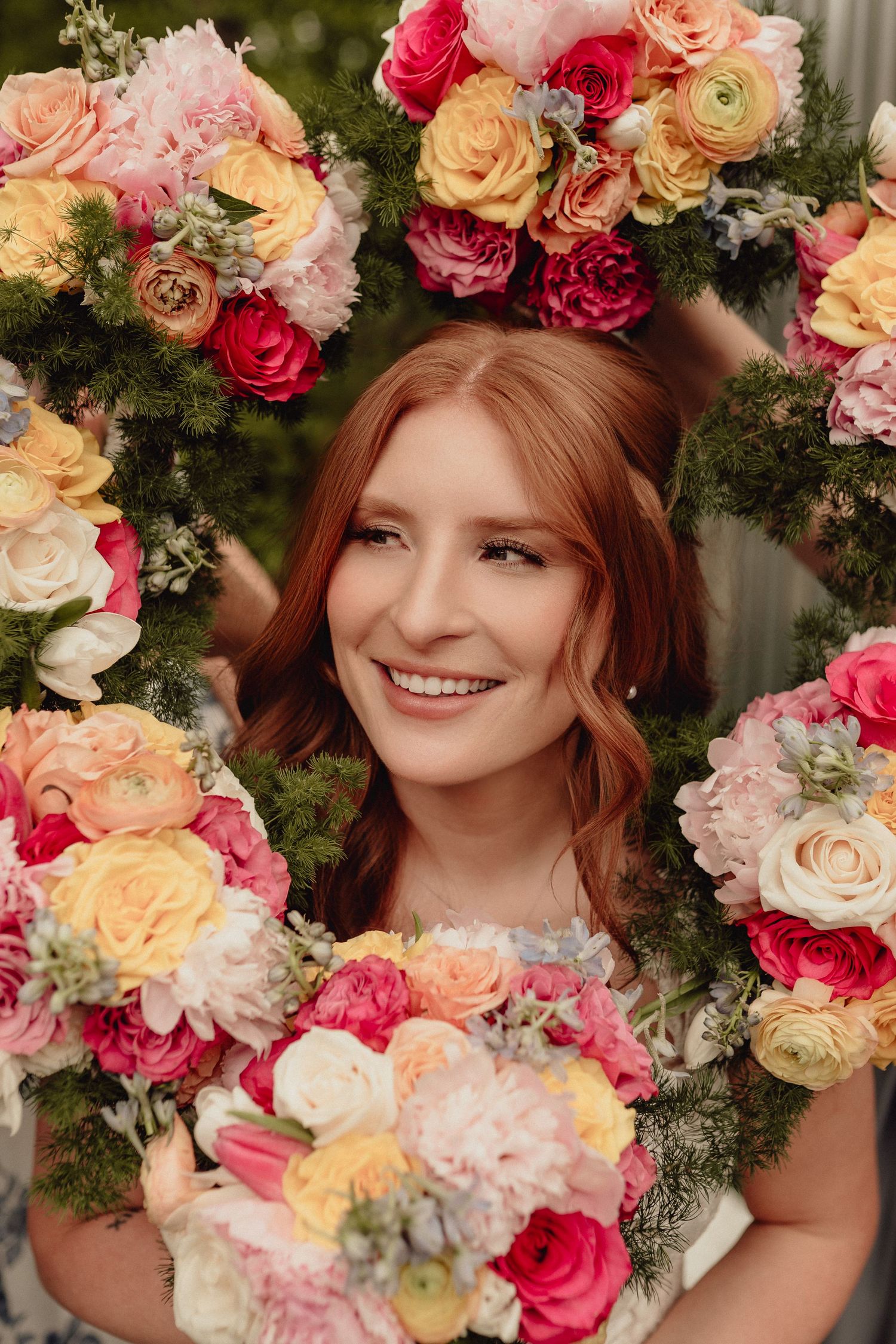 Beautiful floral wreath with pink, peach and white roses and greenery creates a romantic spring display.
