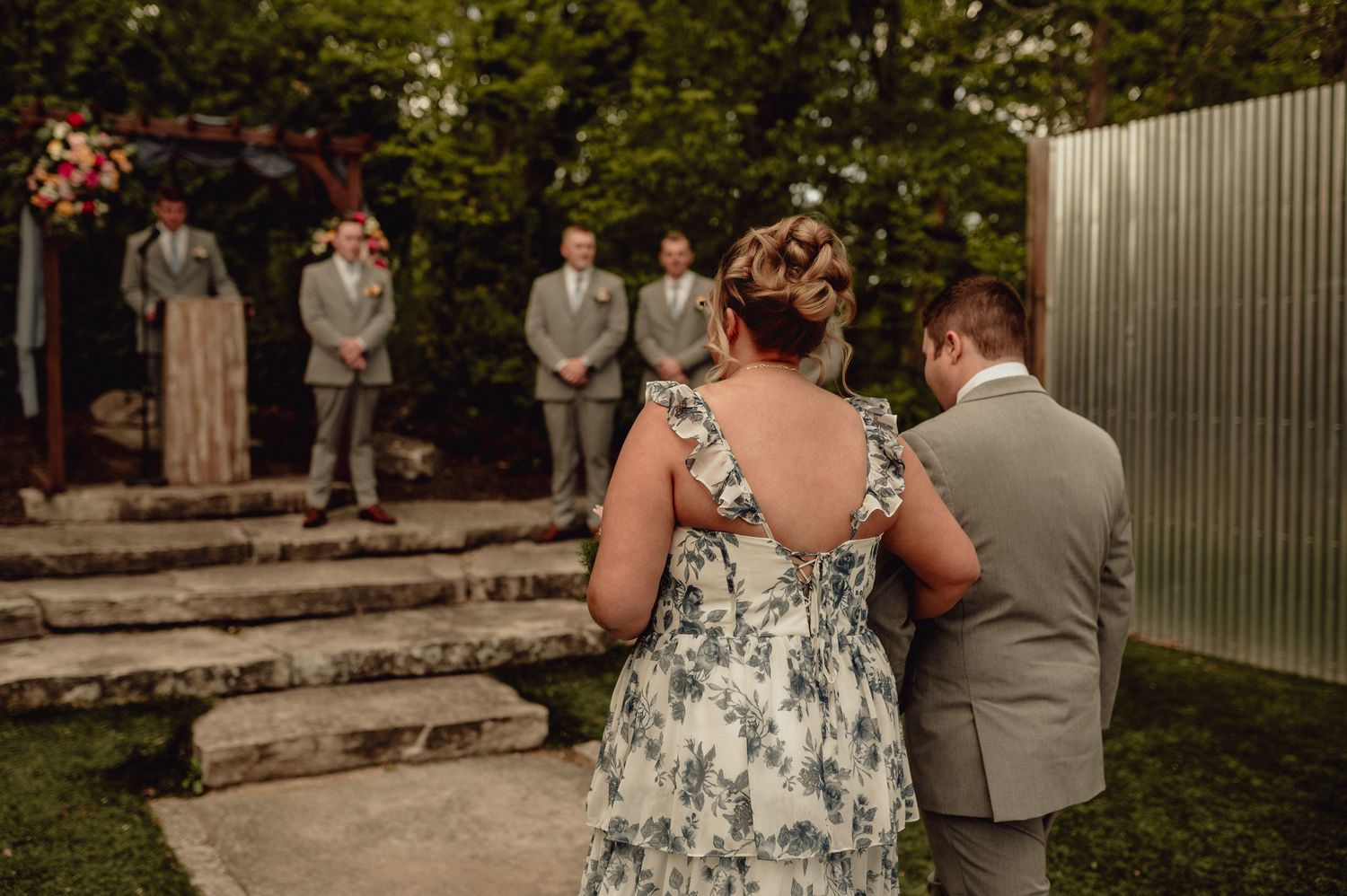 A group of wedding guests gathered outdoors in a garden setting during a summer celebration.