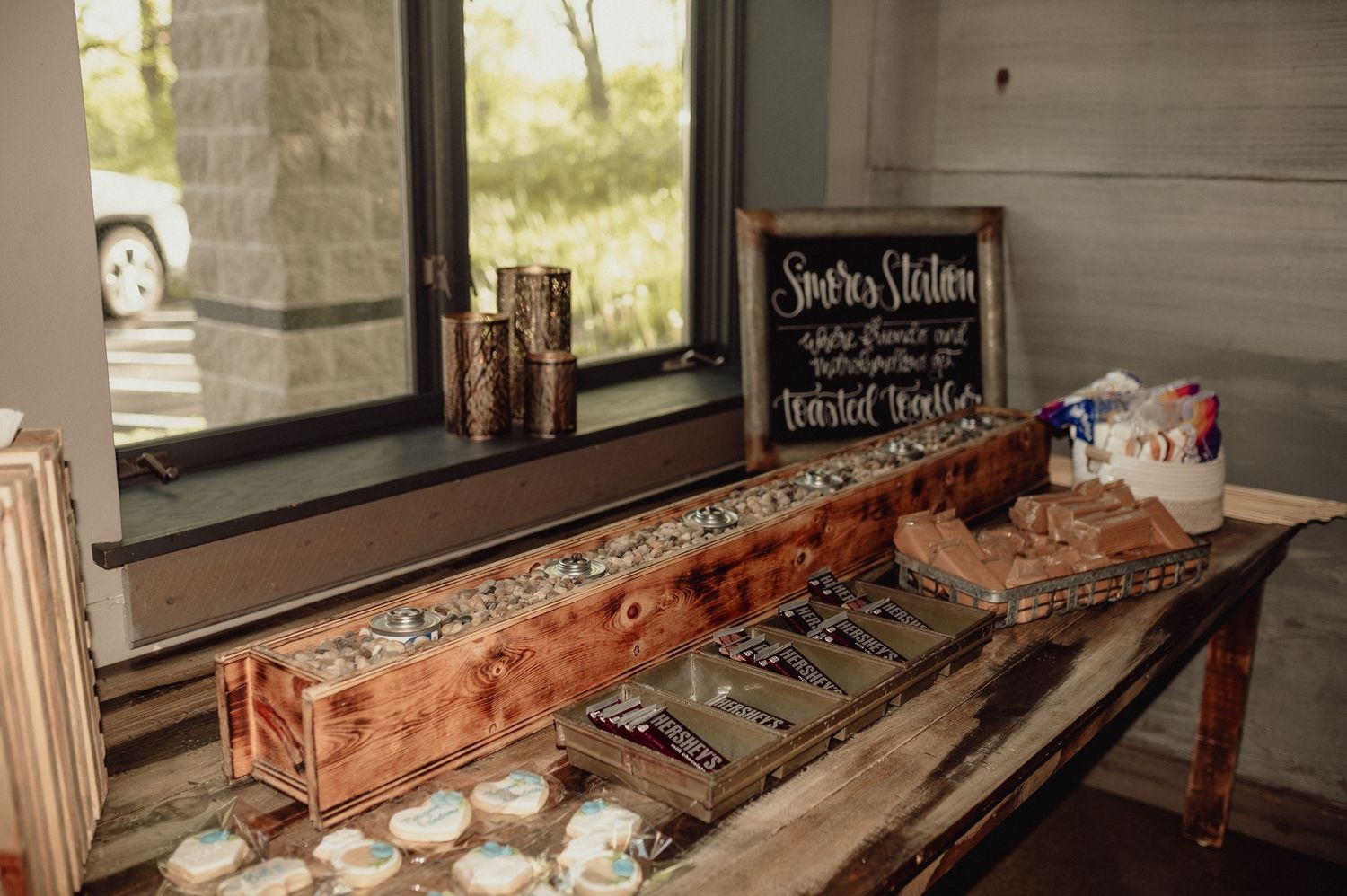 Rustic wooden serving tray with candles and decor items displayed on a table near a window.