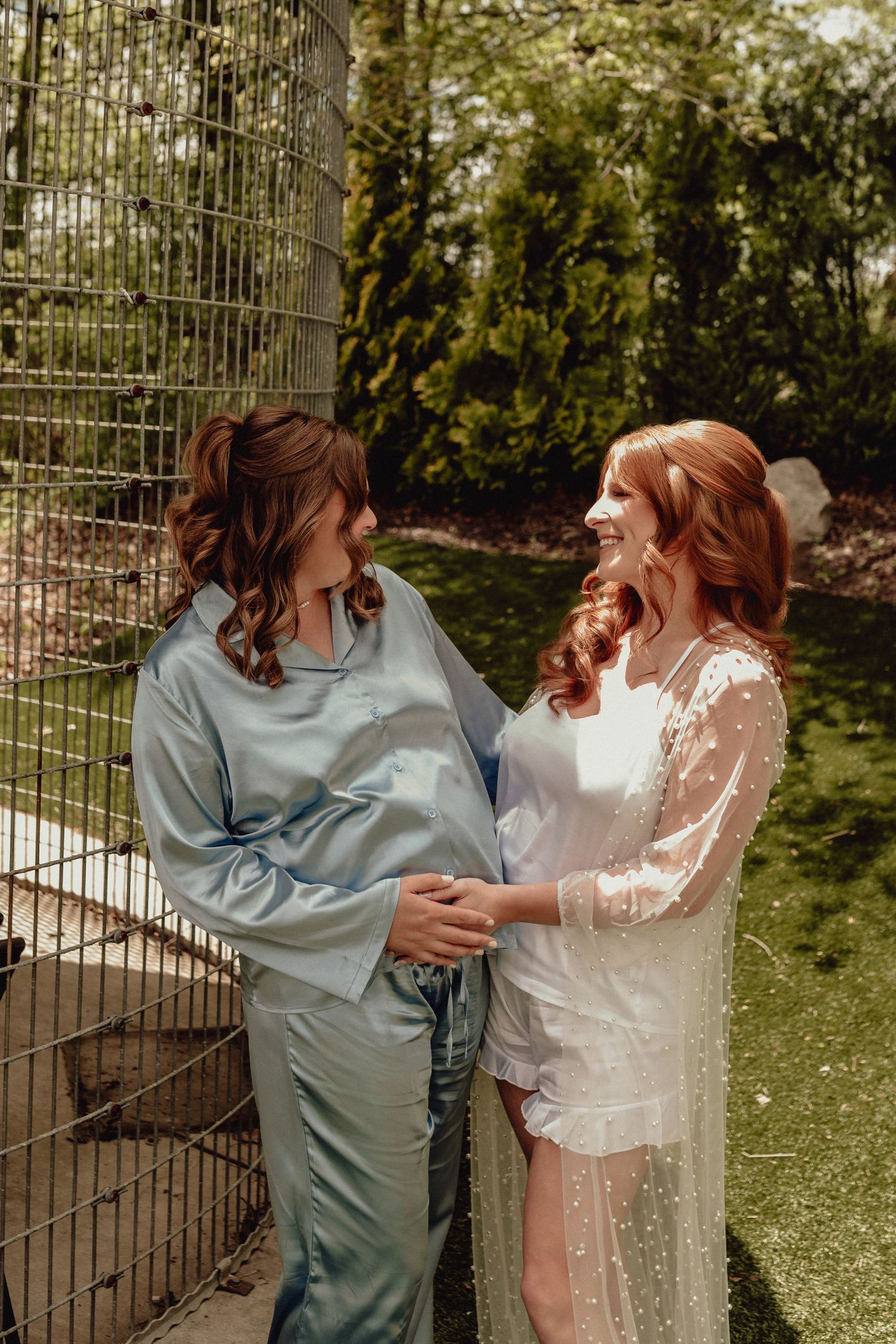 A couple shares a joyful moment in a garden setting wearing contrasting blue and white outfits.