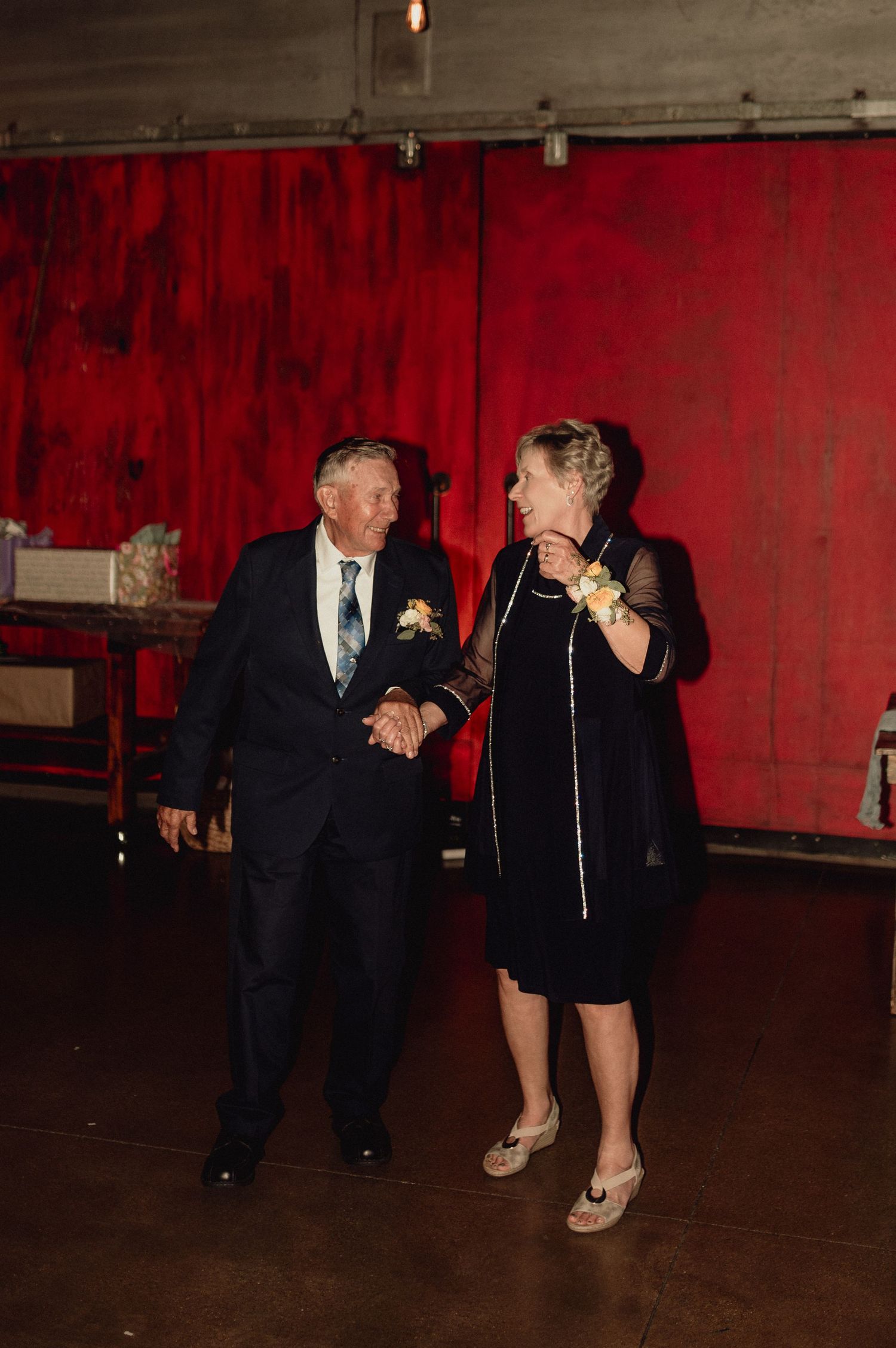 A couple dances together in a dark room with red walls during a romantic evening.