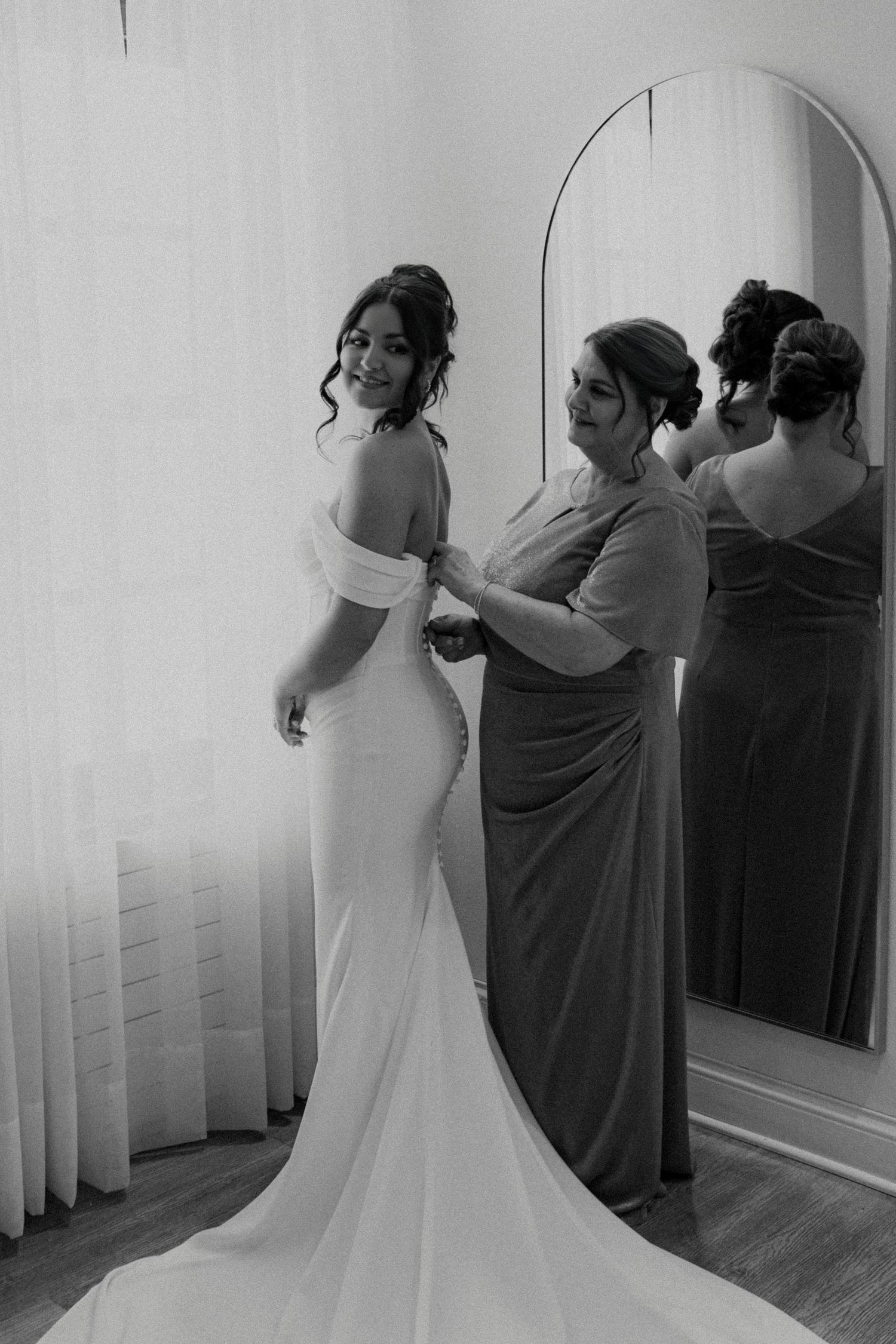 Black and white photo sequence showing a bride getting dressed and fitted into her elegant wedding gown.