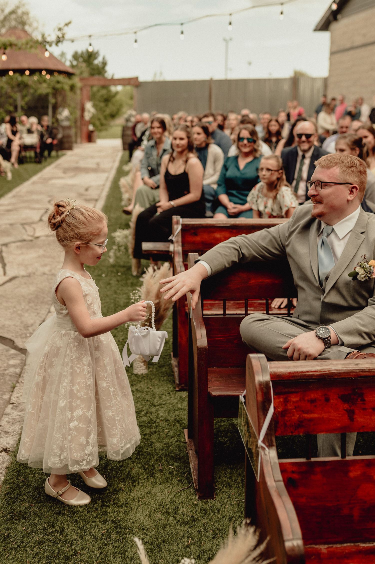 A candid sequence of a couple laughing together on red wooden benches during an outdoor wedding celebration.