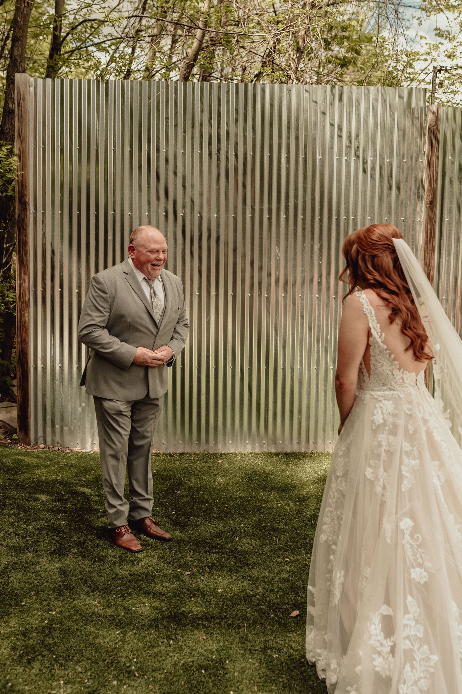 A series of wedding photos showing emotional first look moments between a bride in a floral lace gown and groom in gray suit.
