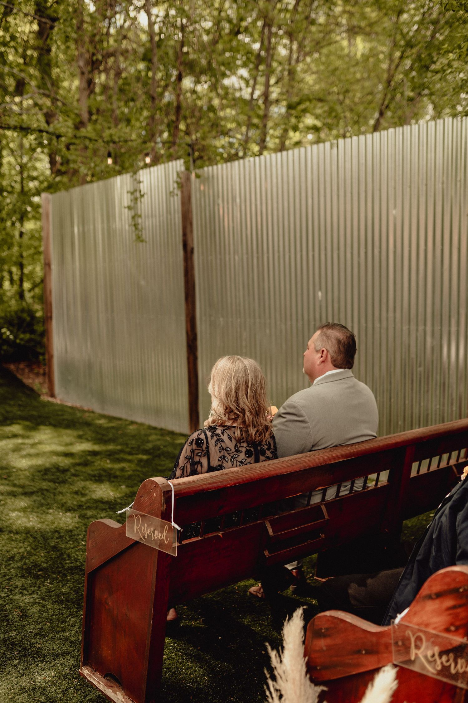 A wooden bench sits against a white picket fence in a serene garden setting during golden hour.