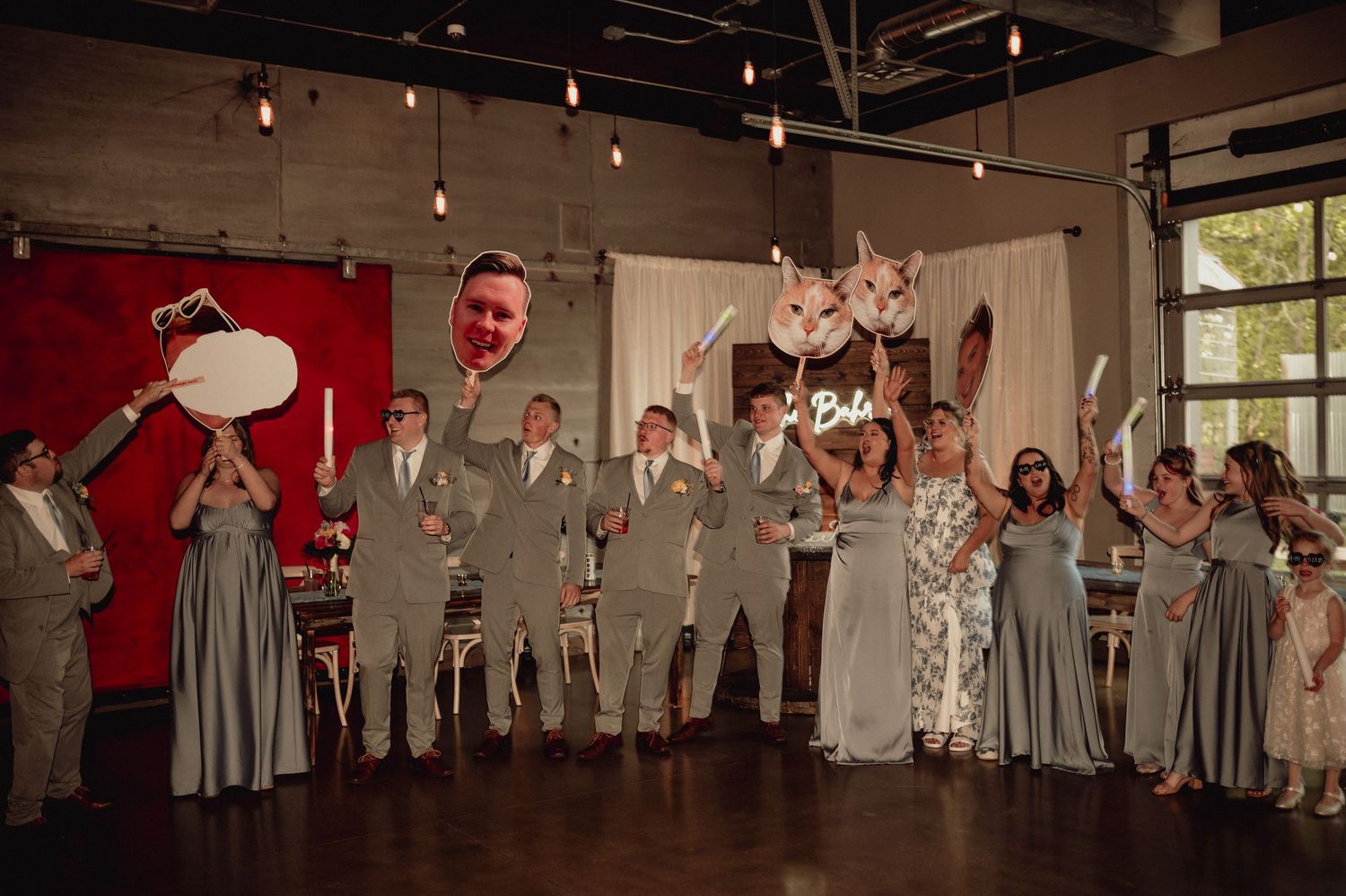 Wedding party members dance together on a wooden floor during a reception celebration.
