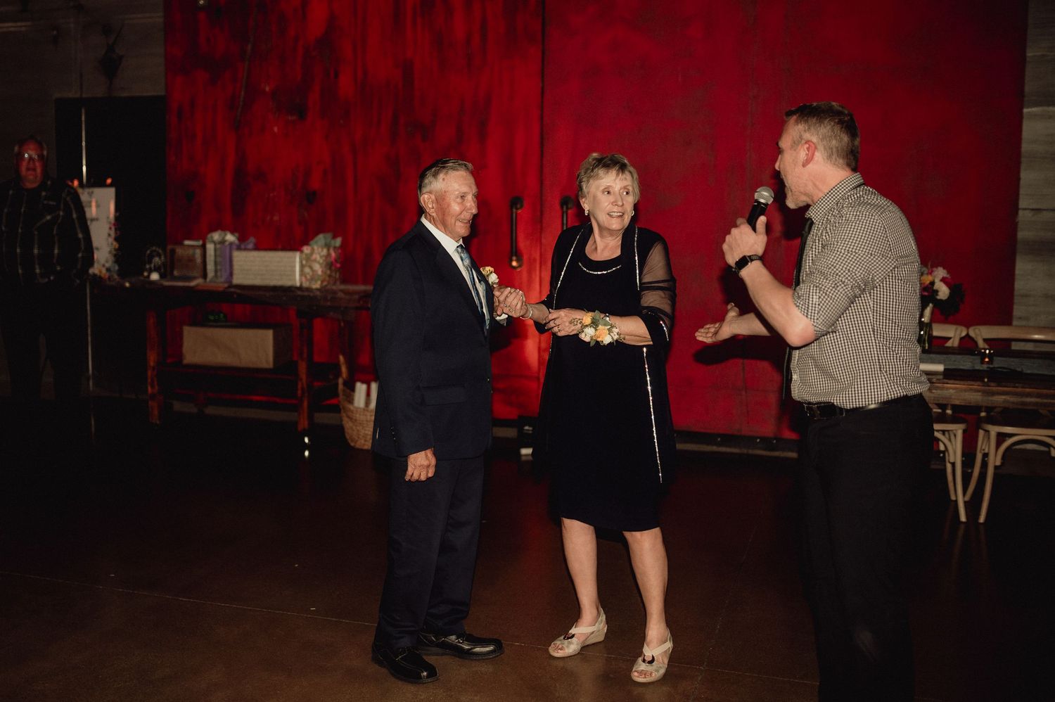 People dancing together in a dimly lit room with red walls during what appears to be a social dance event.