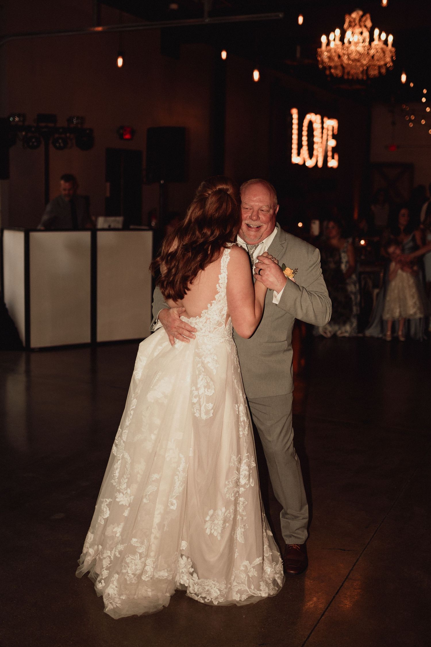 A couple shares a romantic dance moment on a dimly lit dance floor at their wedding reception.