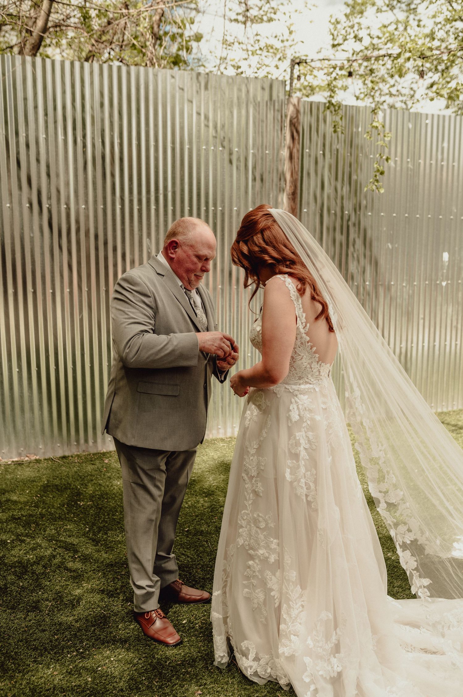 A series of emotional first look moments between a bride in a lace gown and her father in a gray suit outdoors.
