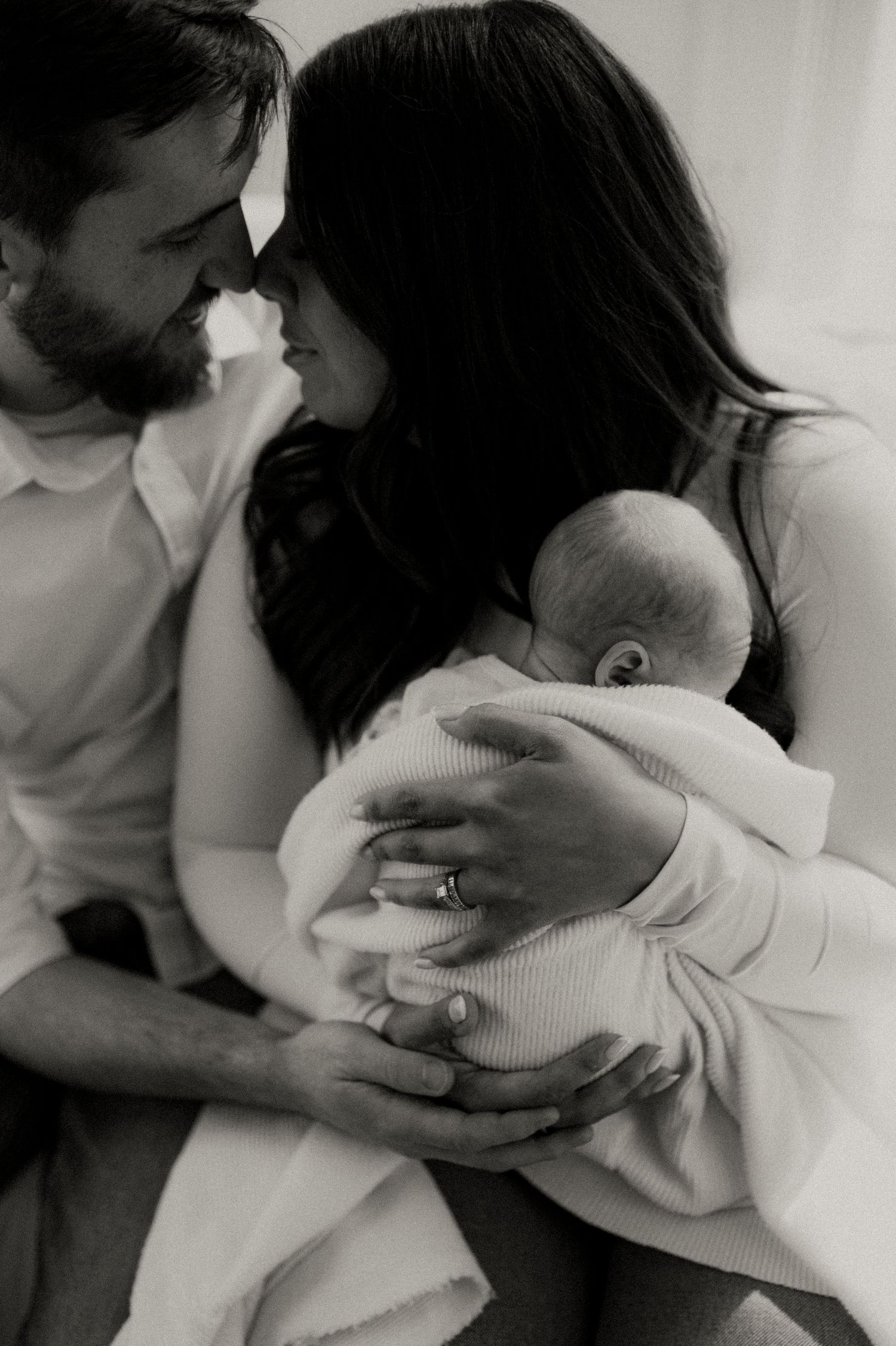 Intimate black and white portrait of couple holding their newborn baby.