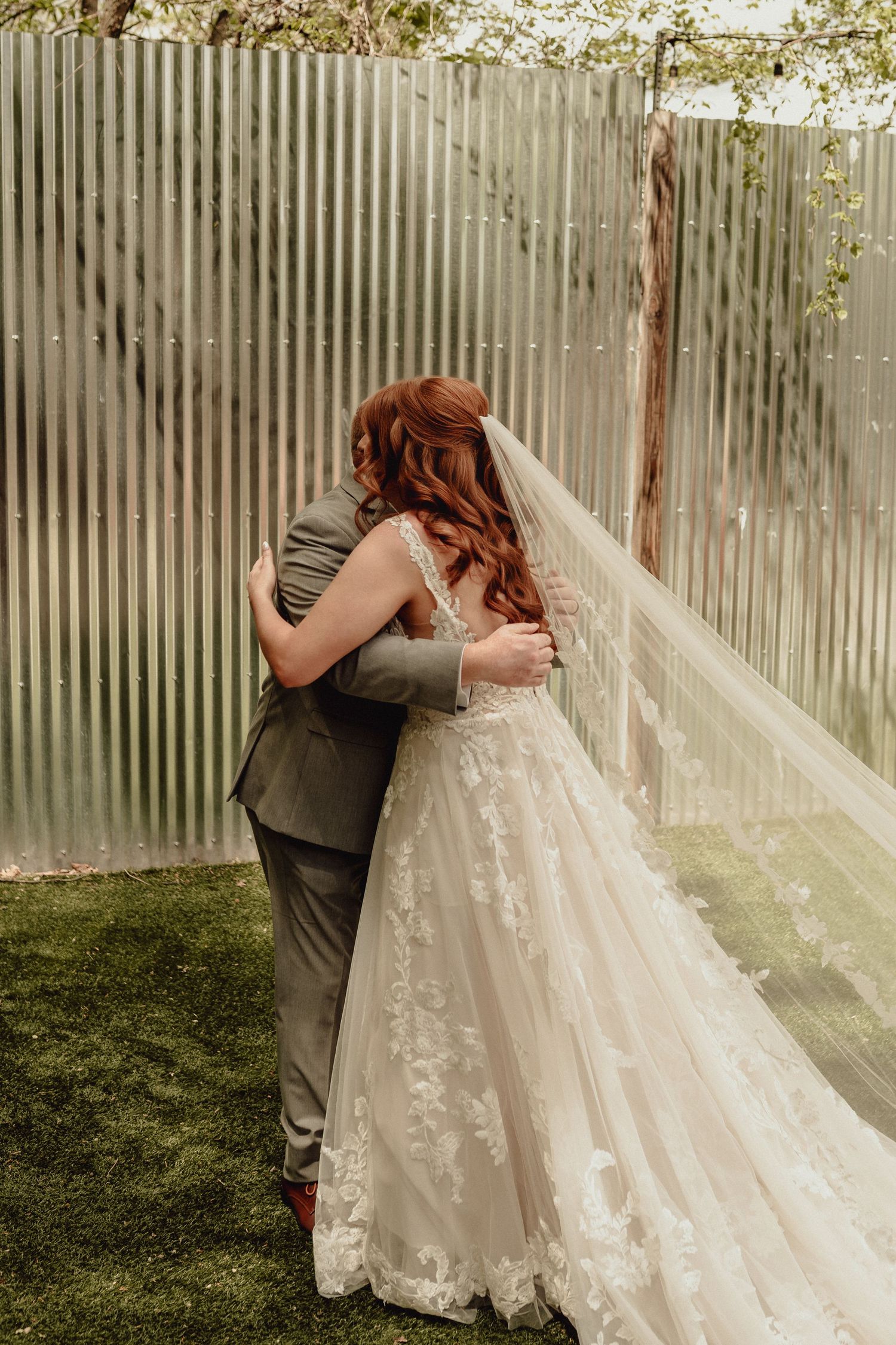 A romantic first look moment between newlyweds in front of a rustic fence with soft natural lighting.