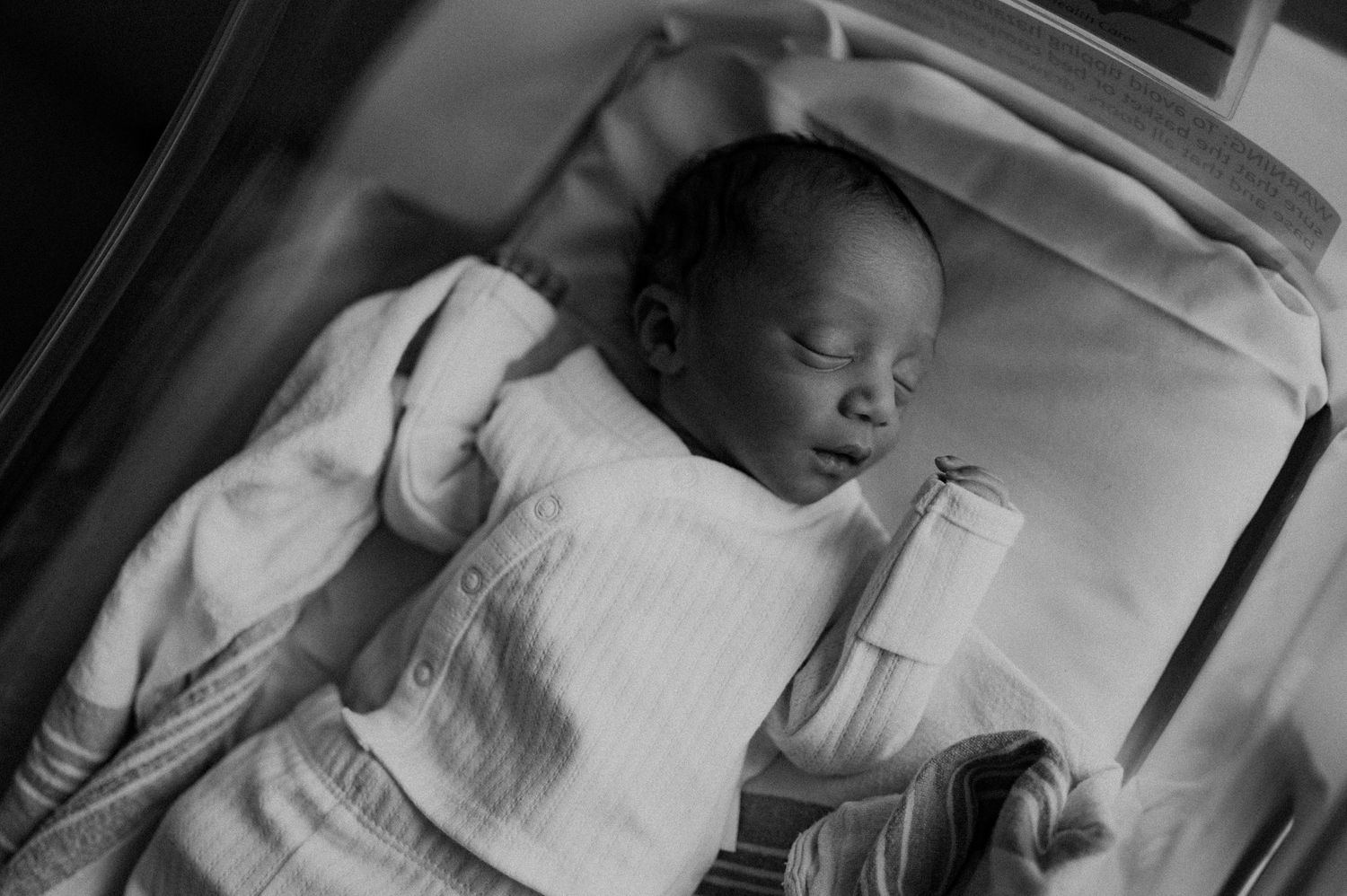 Serene black and white portraits of sleeping newborn in soft white clothing.
