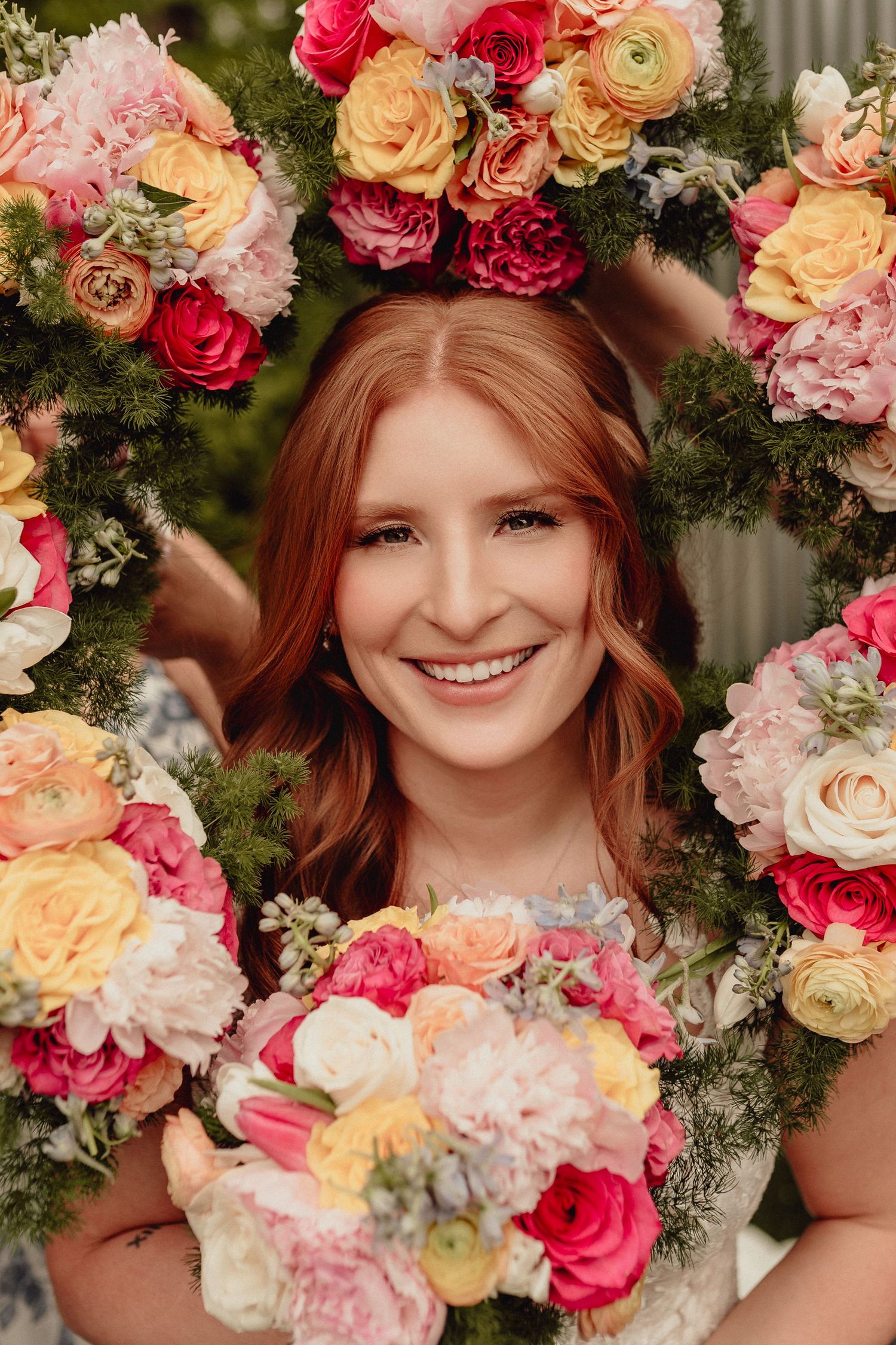 A floral portrait featuring a stunning arrangement of pink, peach and white roses with greenery in a romantic garden setting.
