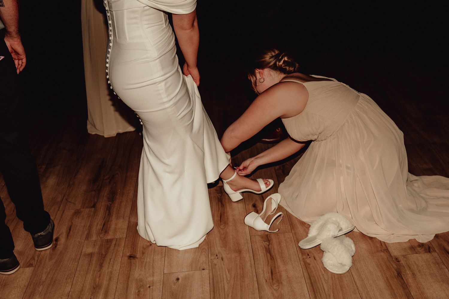A sequence of photos showing a person in a white dress getting help with their shoes on a wooden dance floor.
