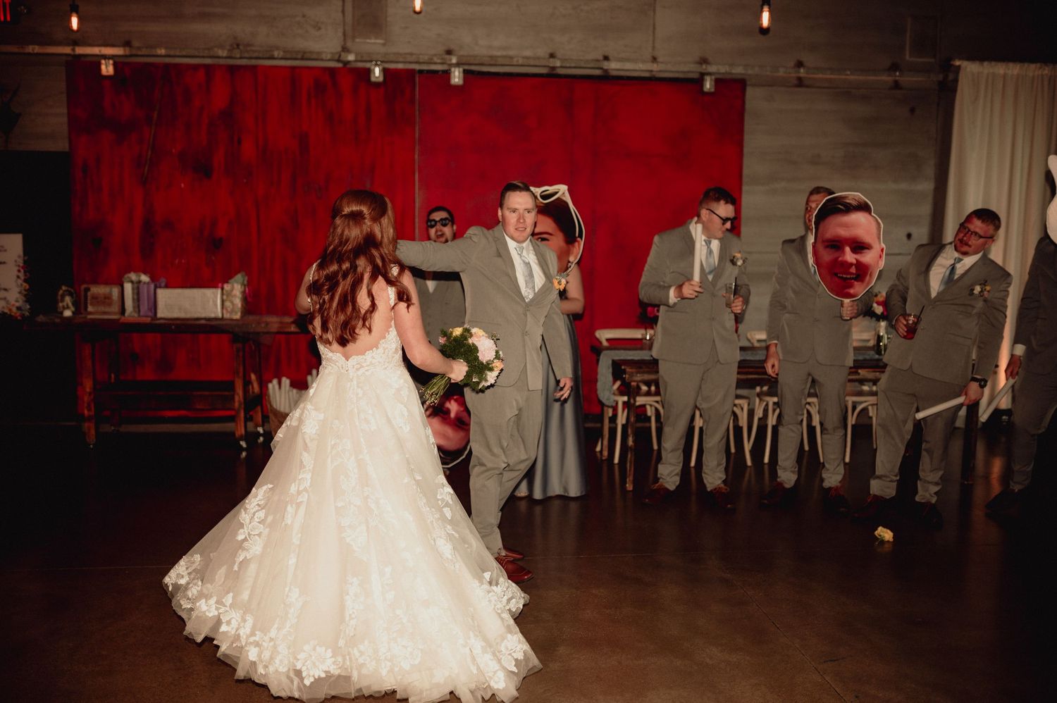 A wedding couple dances together on a spacious wooden floor during their first dance at a reception venue.
