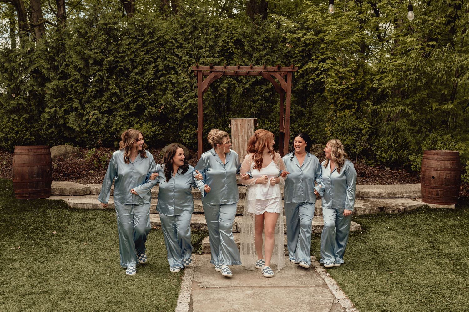 Group of people in coordinated pastel and denim outfits sitting together on stone steps in a garden setting.