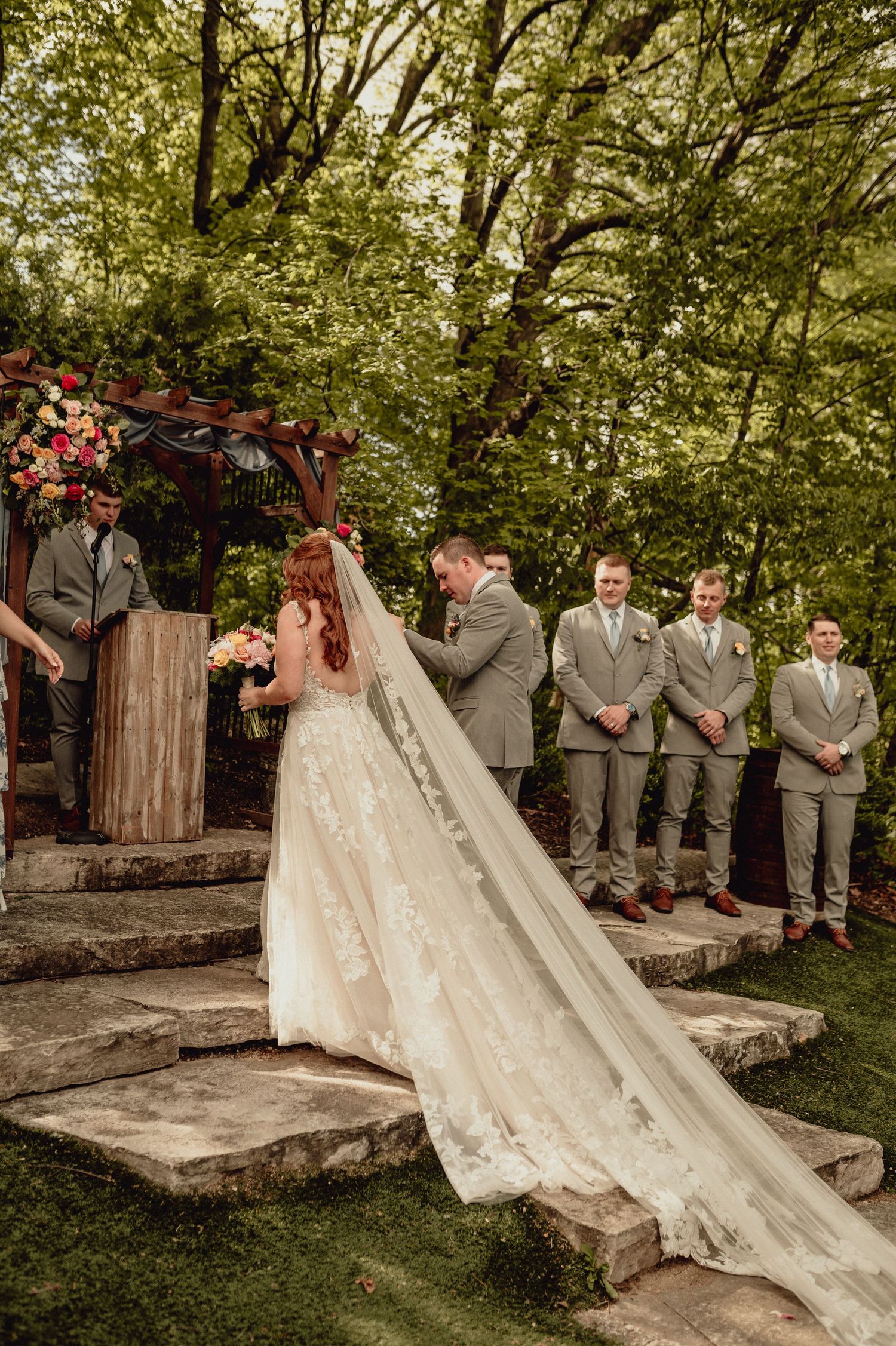 A romantic wedding scene unfolds across multiple photos showing a couple and wedding party on rustic stone steps surrounded by greenery.