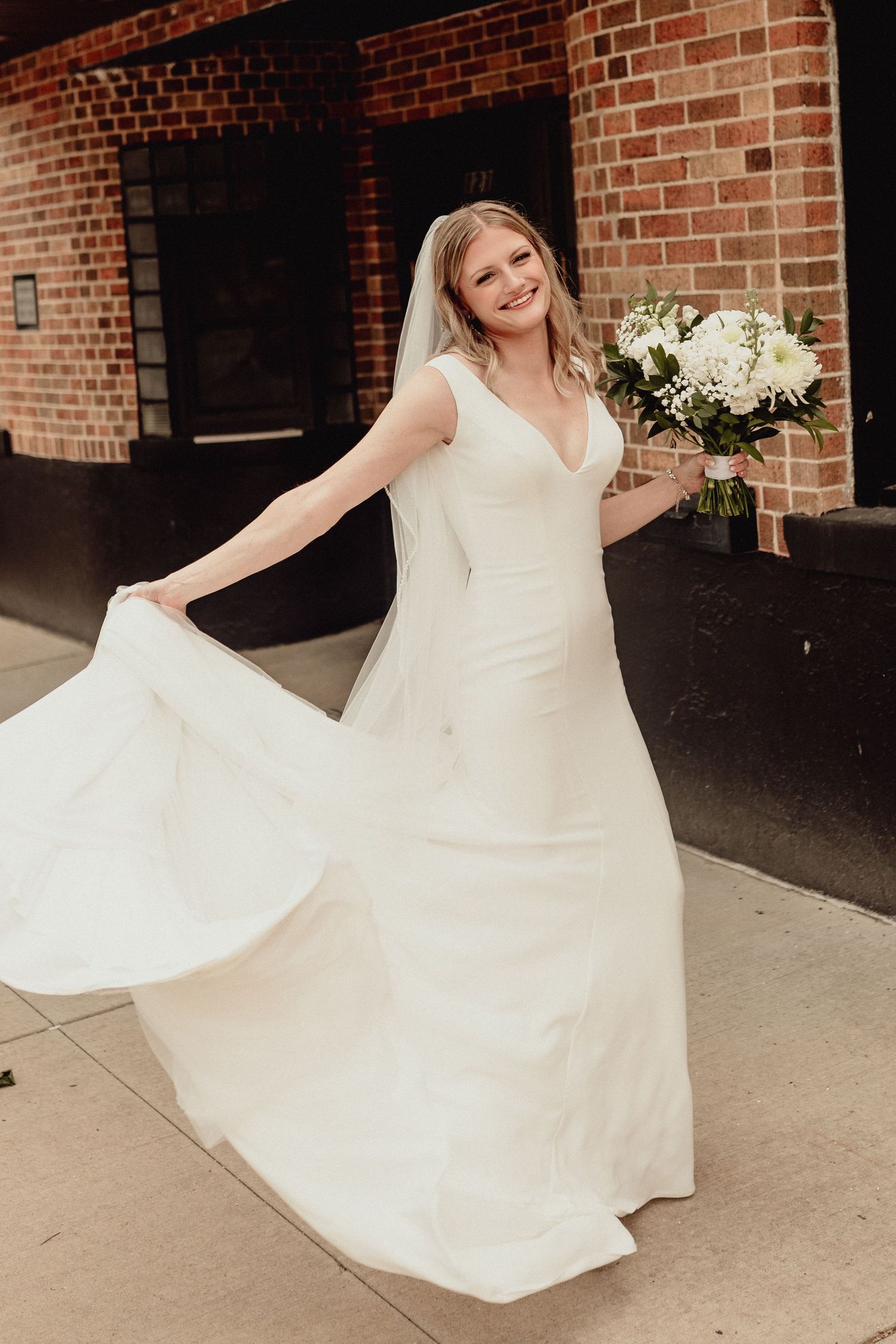 A flowing white dress twirls against a brick building backdrop.