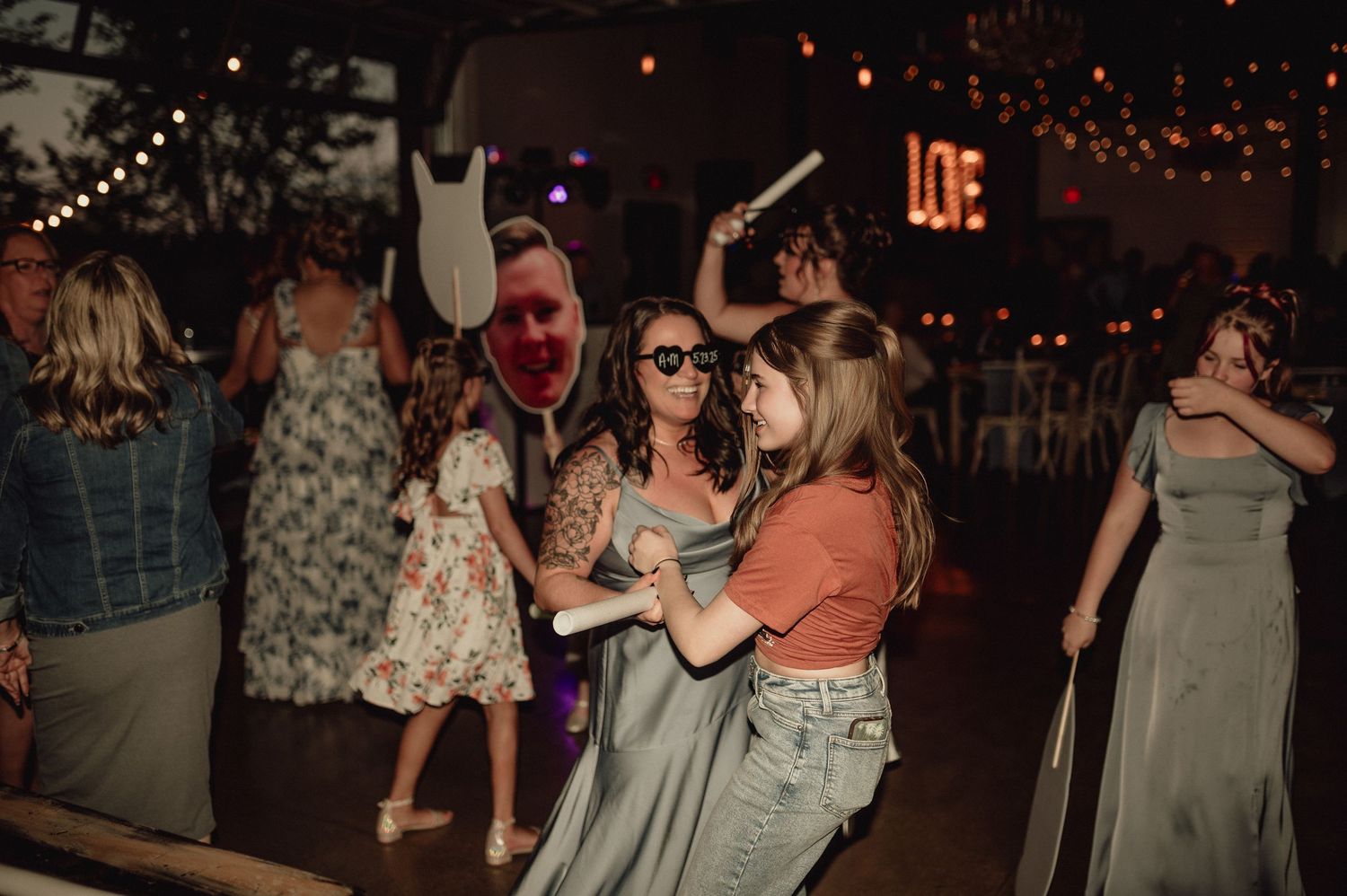 People dancing and socializing at a dimly lit nightclub or party venue with string lights overhead.