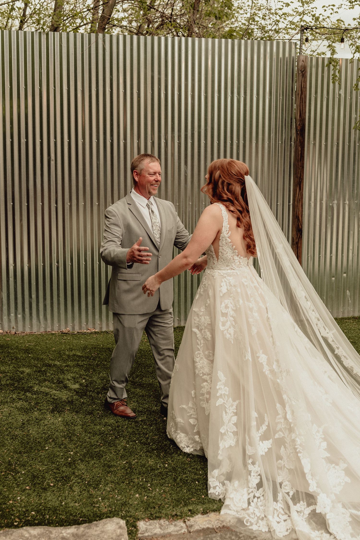 Multiple shots capture a first look moment between newlyweds, featuring a stunning lace wedding dress with cathedral veil.