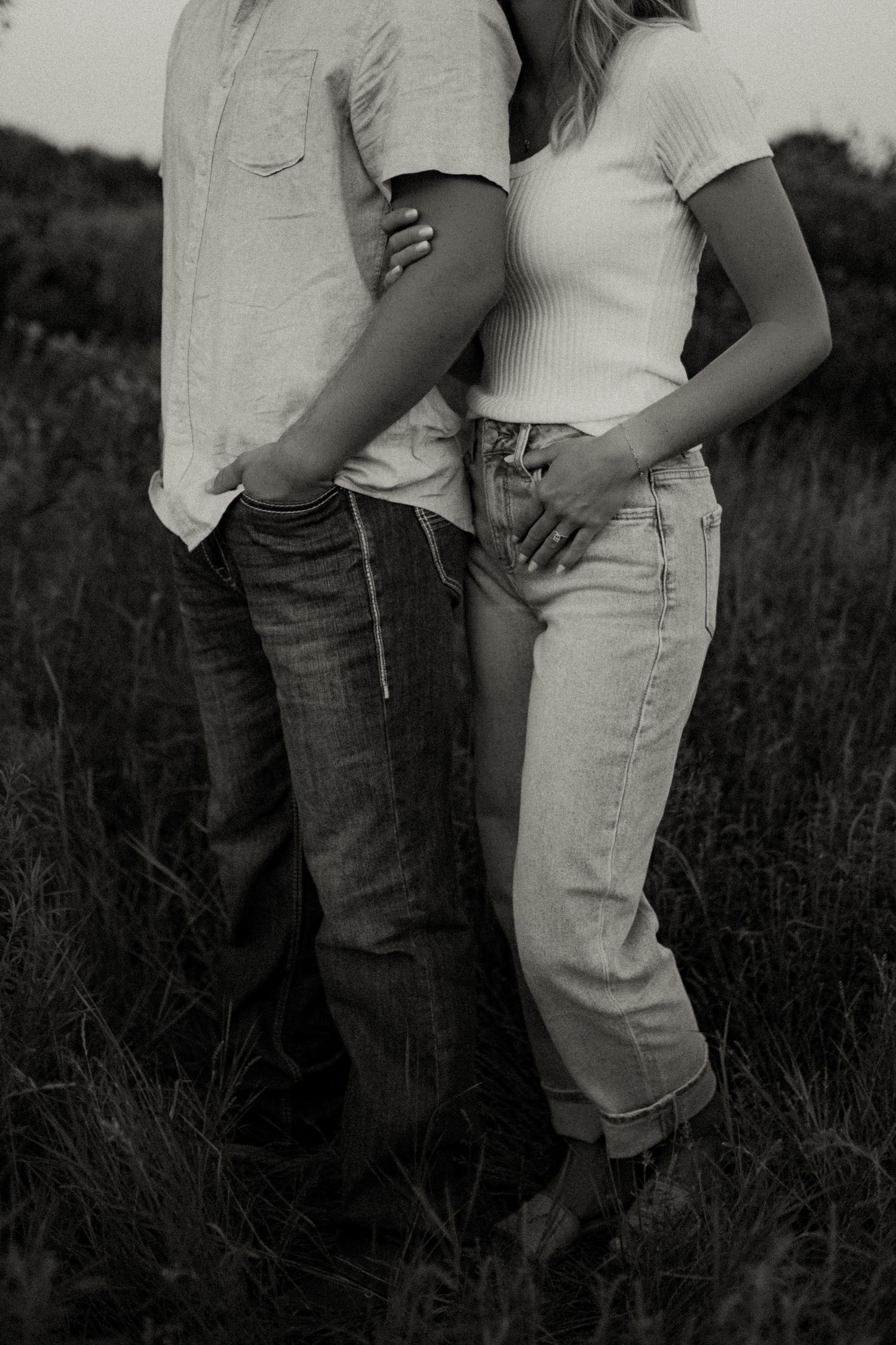 Intimate black and white photograph of people in casual attire standing in tall grass.