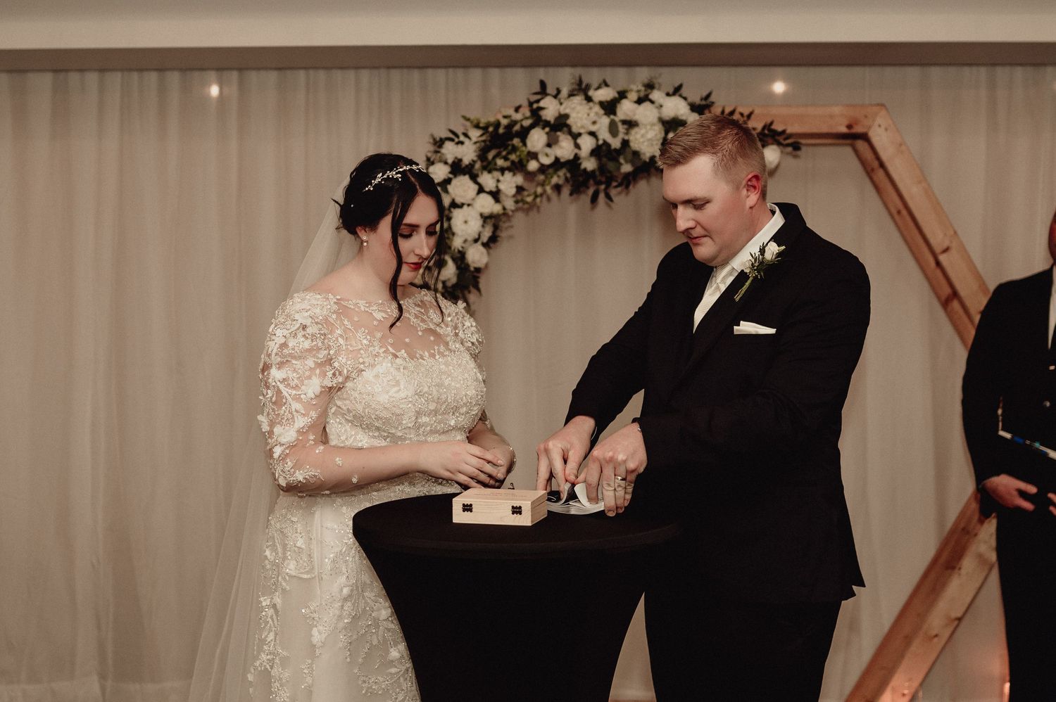 A couple exchanges rings during an elegant indoor wedding ceremony with soft lighting and romantic atmosphere.
