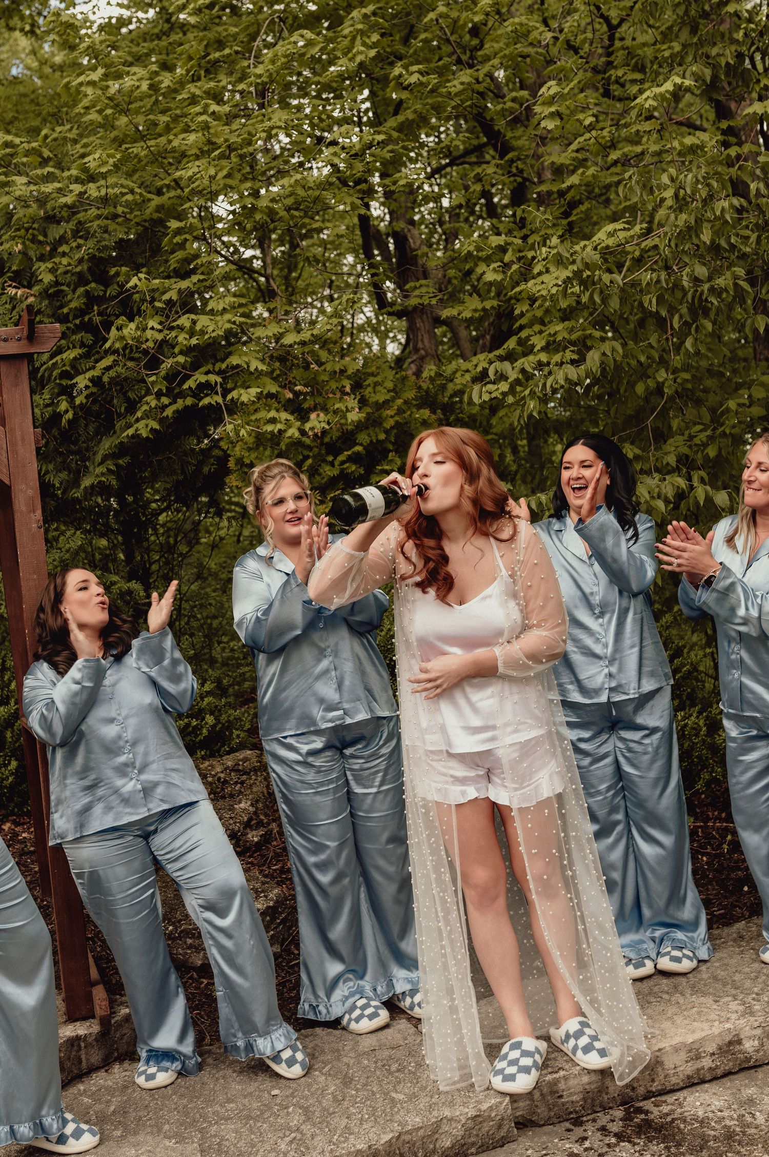 Wedding party in matching gray jumpsuits striking fun poses outdoors.