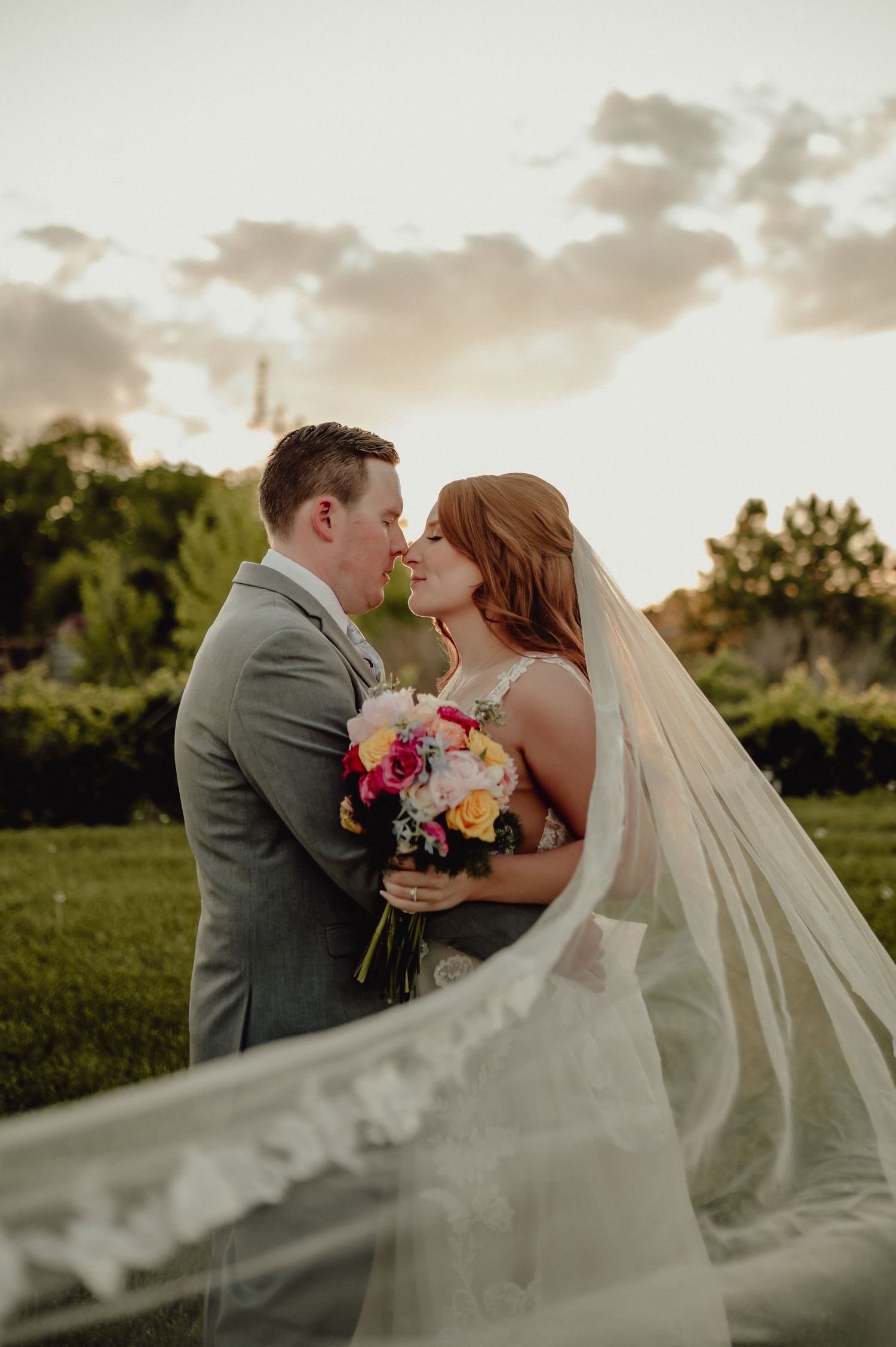 A romantic wedding photo series shows a couple embracing in a garden at sunset with a flowing veil and colorful bouquet.