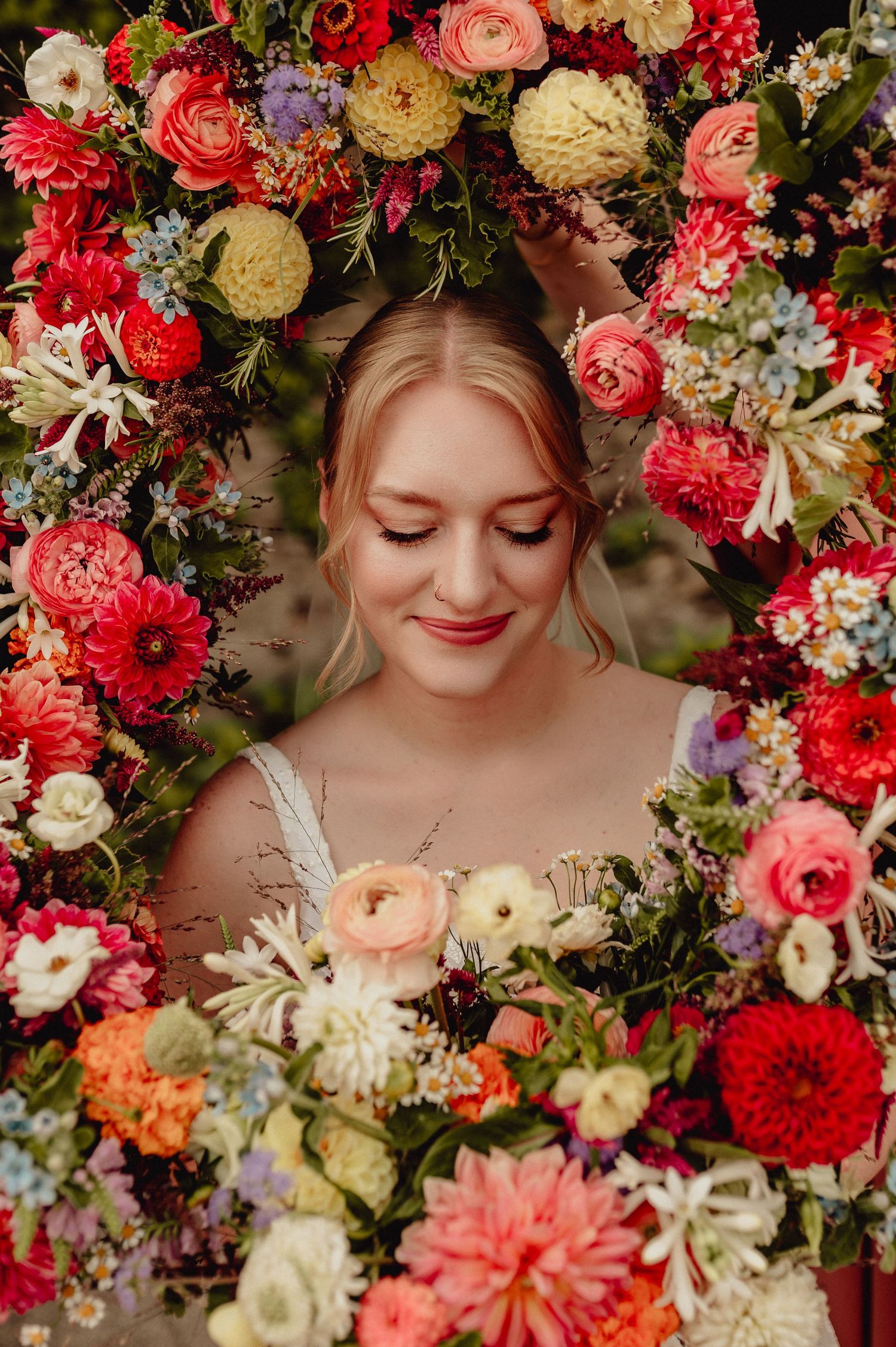 Romantic portrait surrounded by lush red, pink and white floral arrangements.