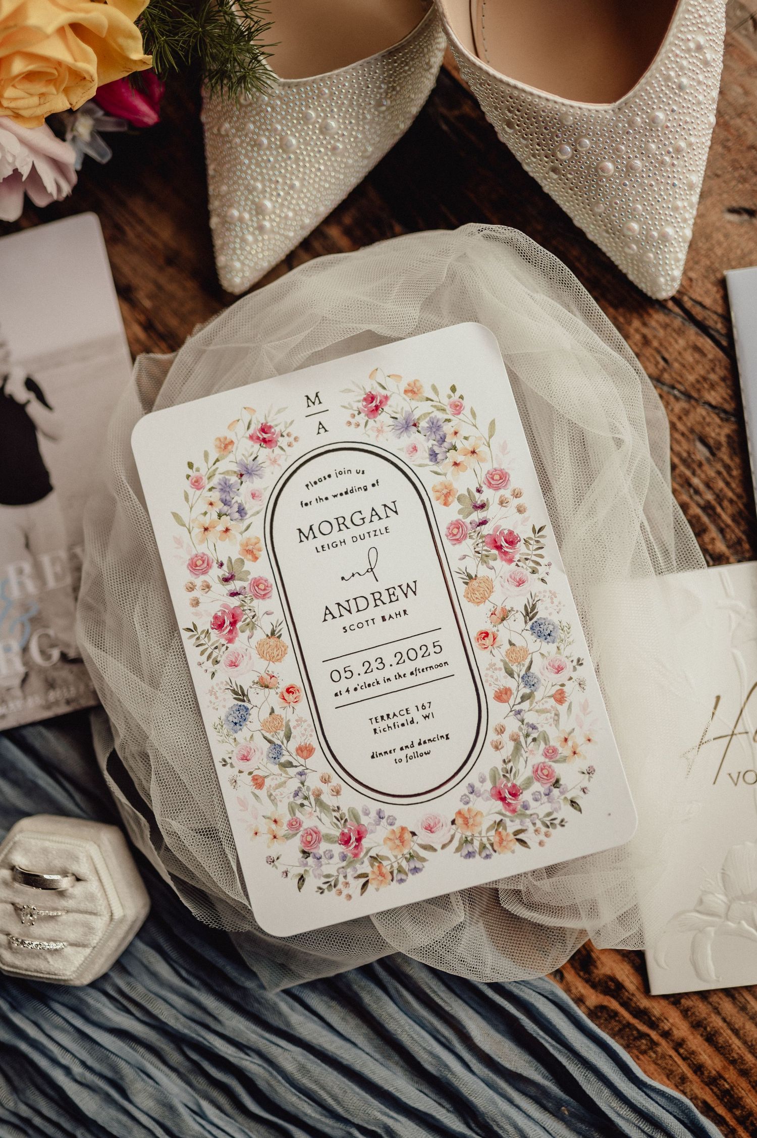 Wedding invitation cards with floral designs and elegant typography displayed on a rustic wooden surface.