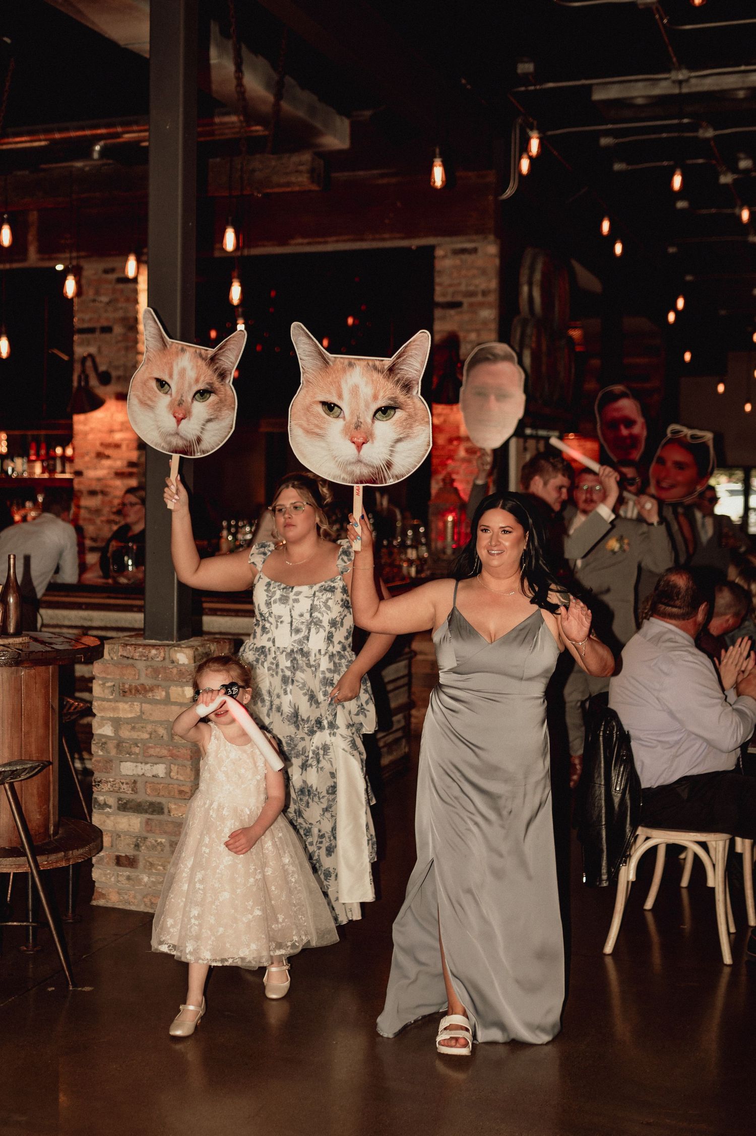 Wedding party dances in sequence wearing bunny head masks in a dimly lit reception venue with hanging lights.